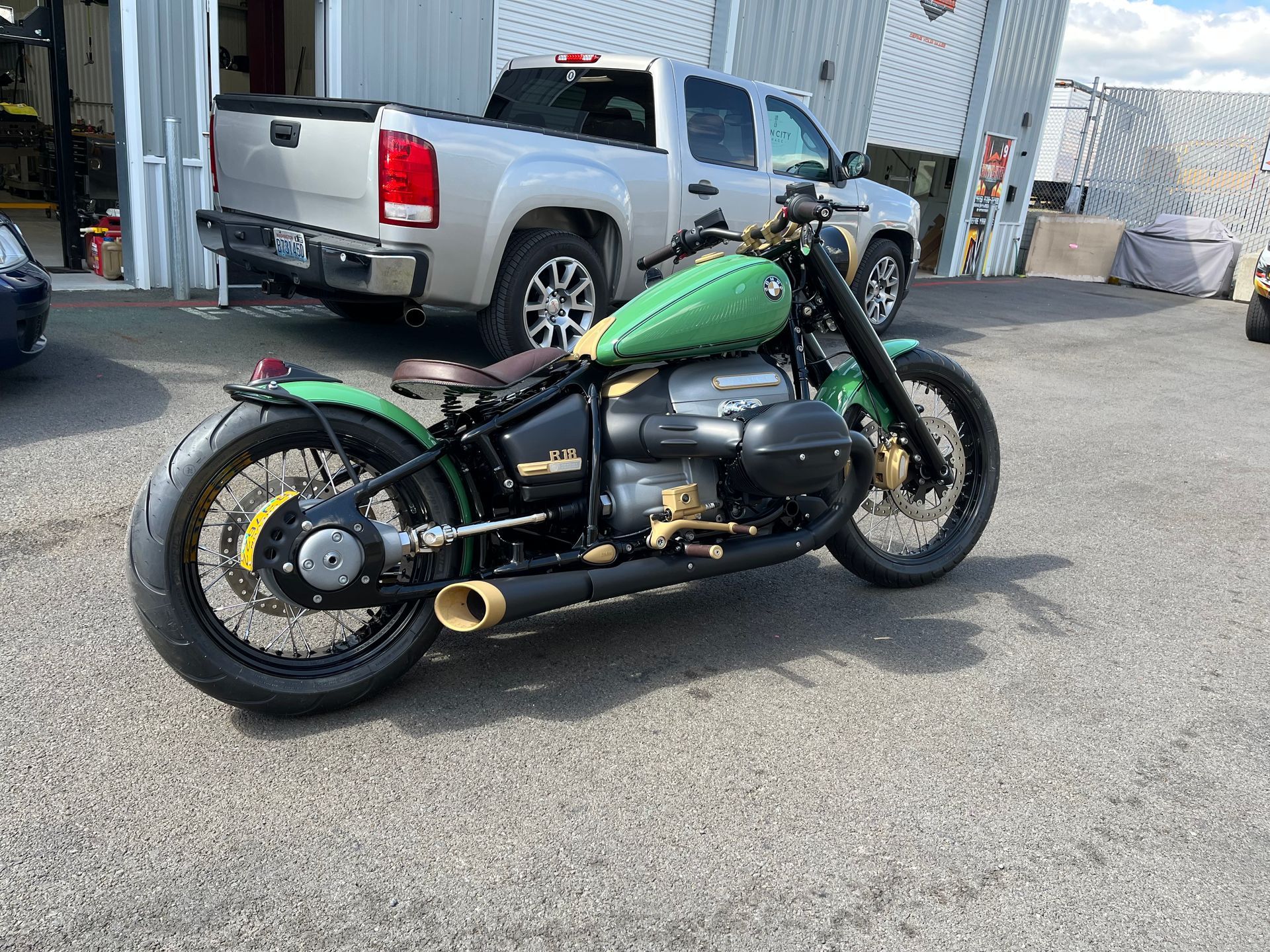 A green motorcycle is parked in a parking lot next to a truck.