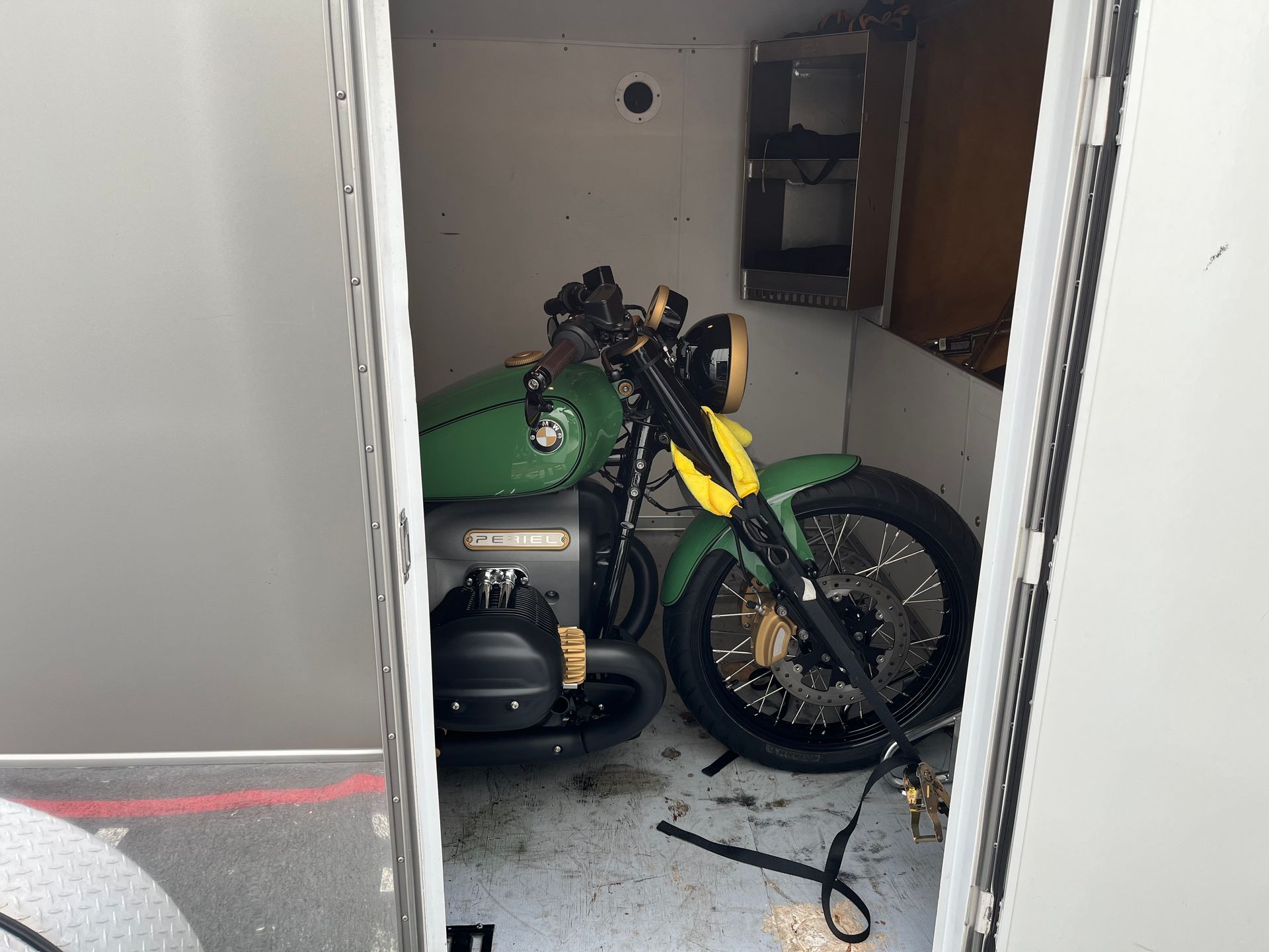 A green motorcycle is parked inside of a trailer.