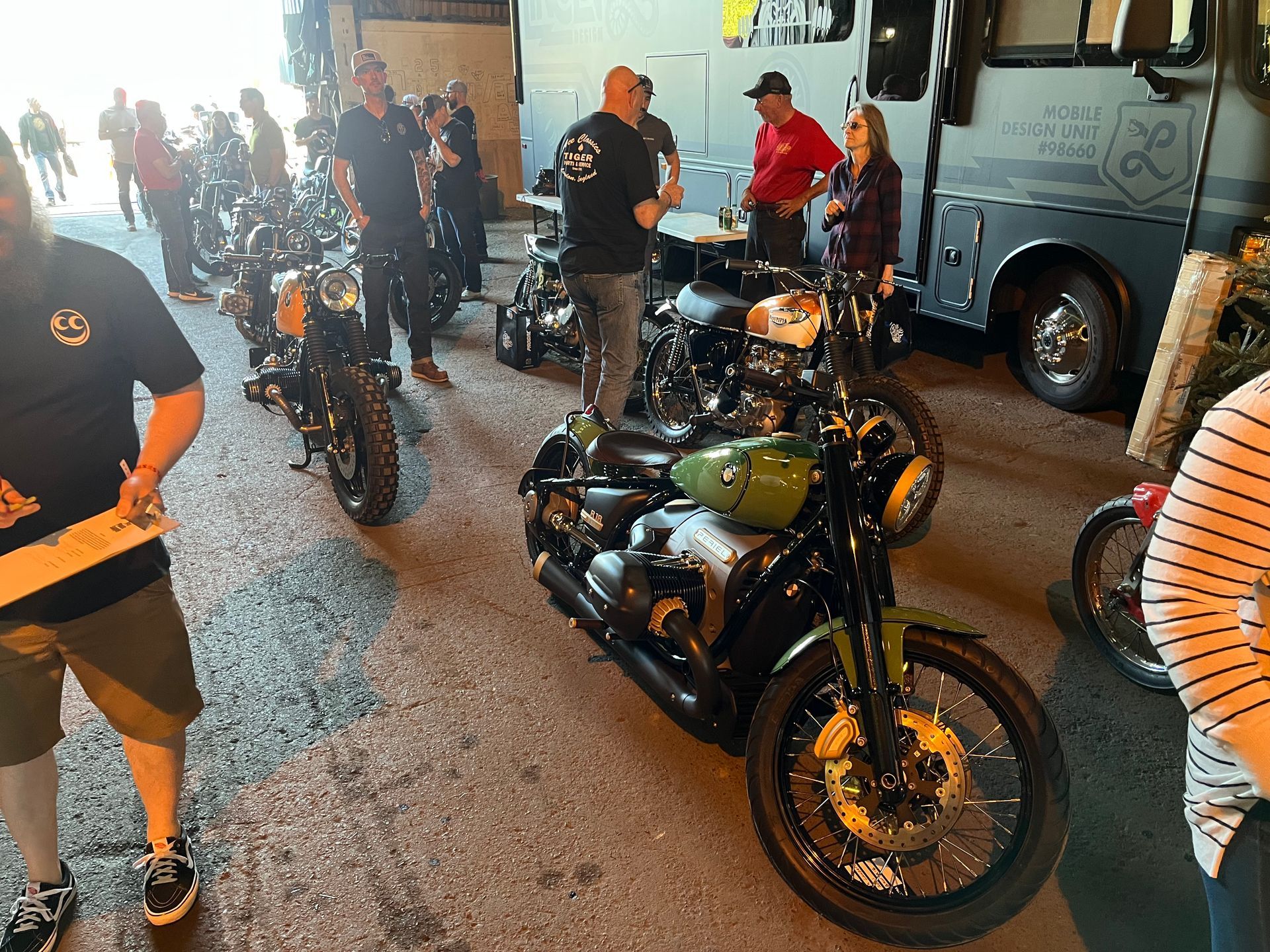 A group of people are standing around motorcycles in a parking lot.