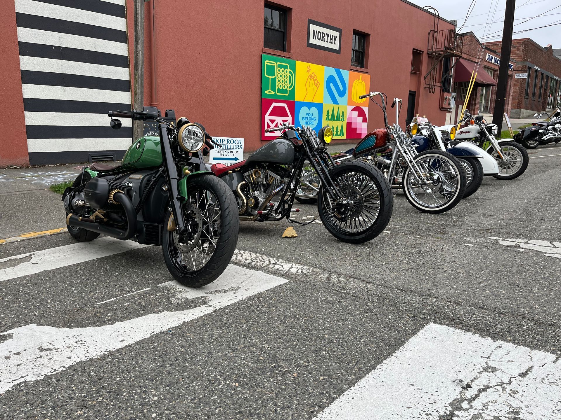 A row of motorcycles are parked on the side of the road in front of a building.