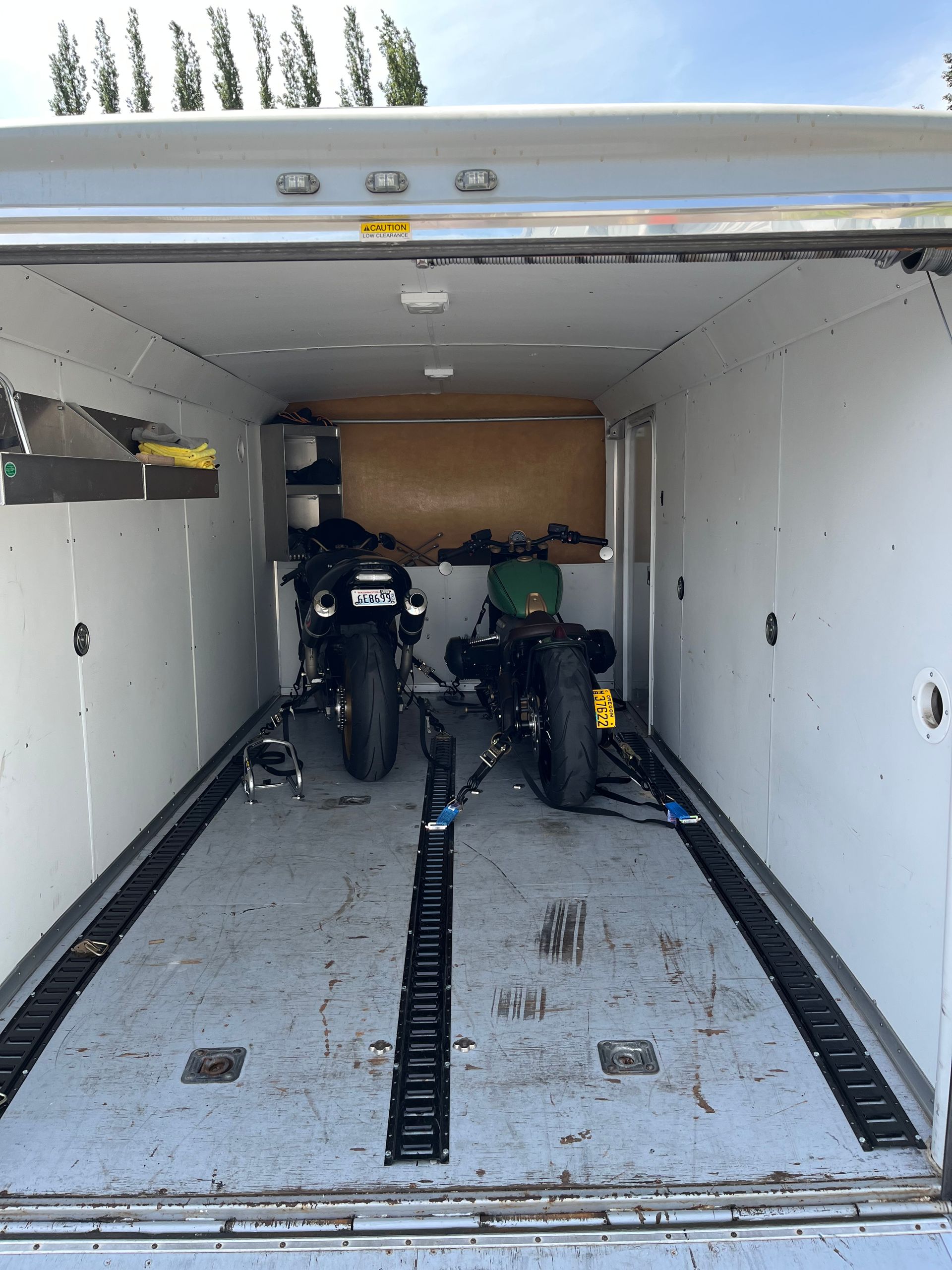 Two motorcycles are parked inside of a trailer.