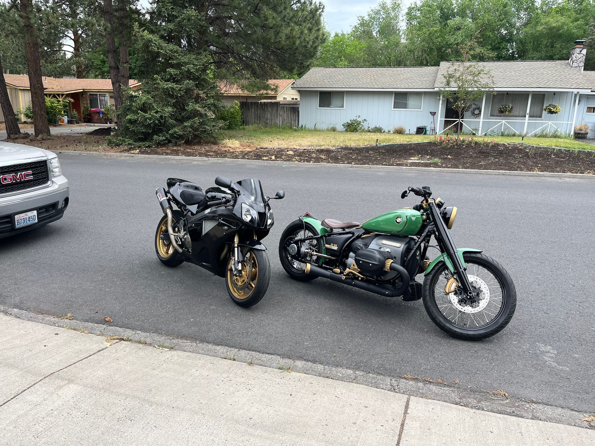 Two motorcycles are parked on the side of the road next to a car.