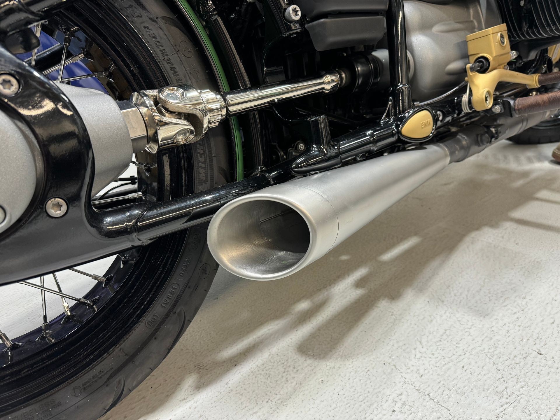A close up of a motorcycle exhaust pipe on a white floor.
