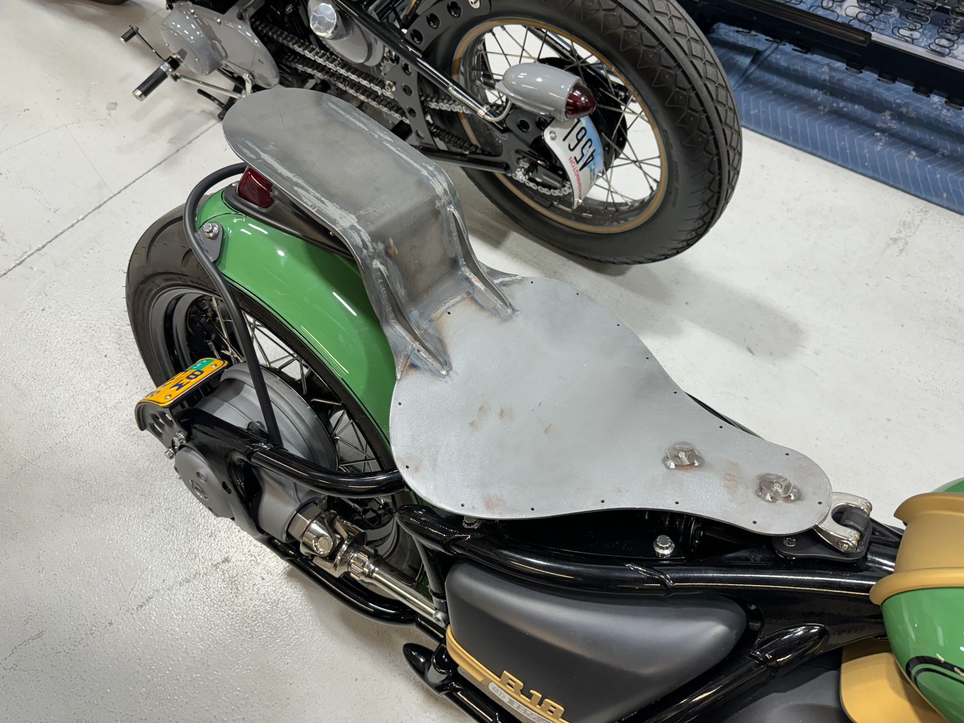 A green motorcycle is parked next to a black motorcycle in a garage.