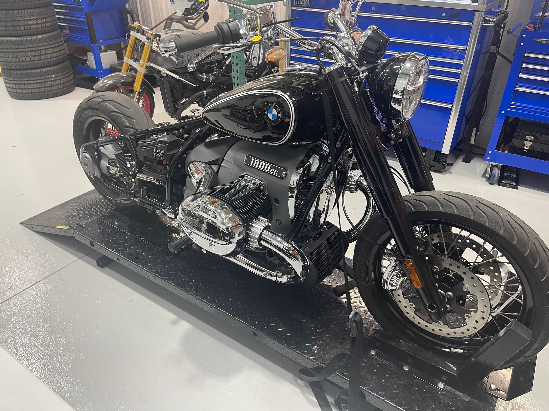 A black motorcycle is parked on a ramp in a garage.