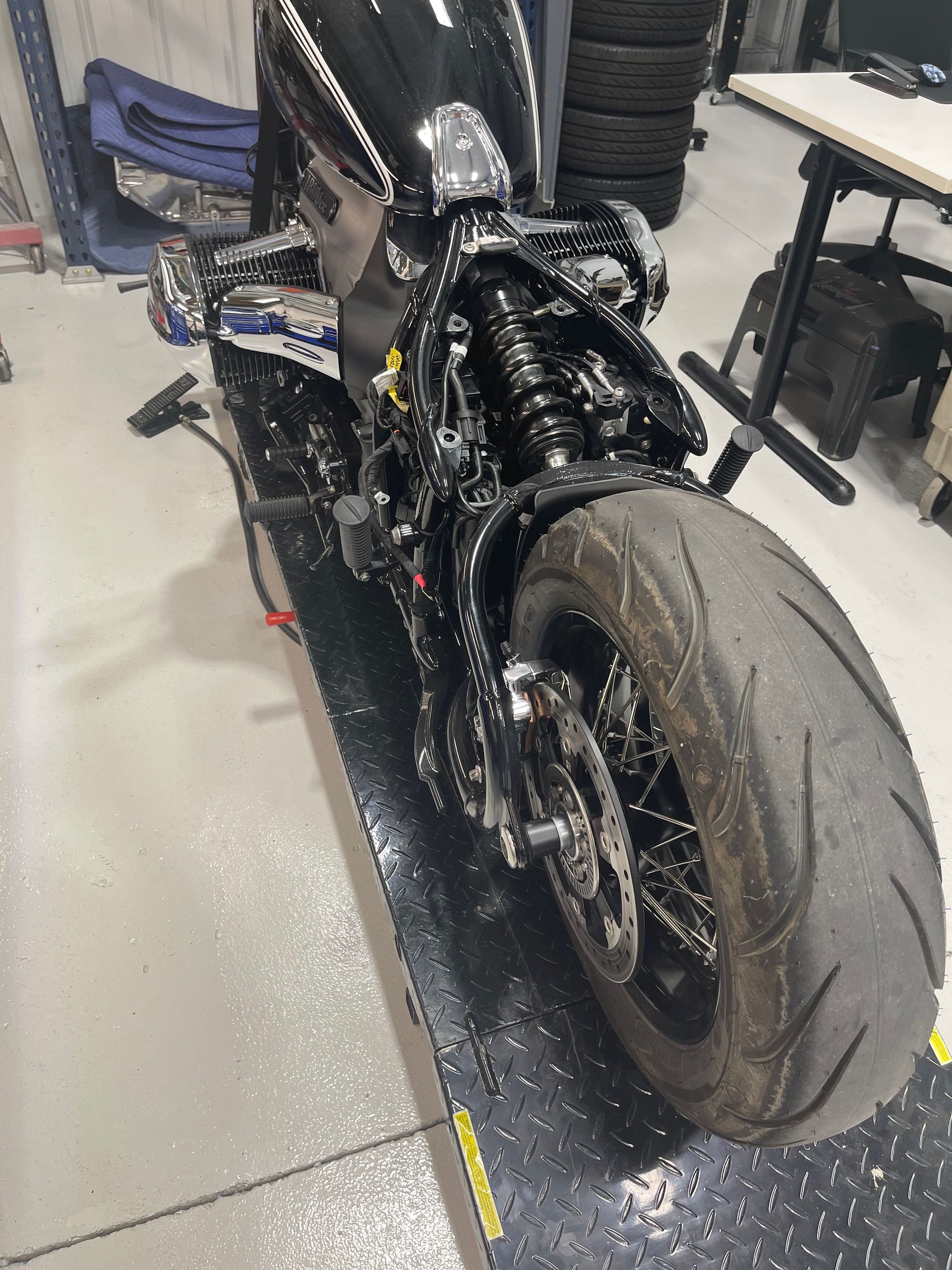 A black motorcycle is parked in a garage next to a table.