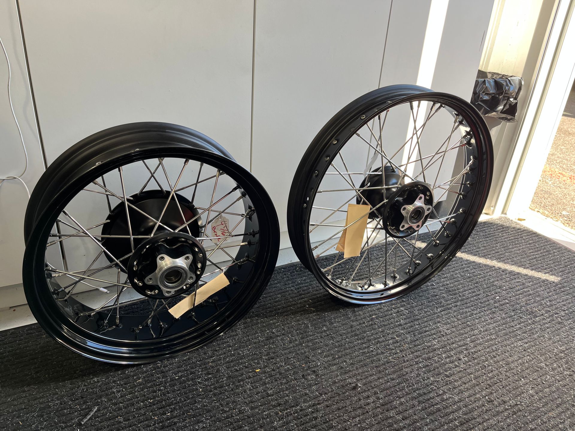 Two black motorcycle wheels are sitting on a carpeted floor