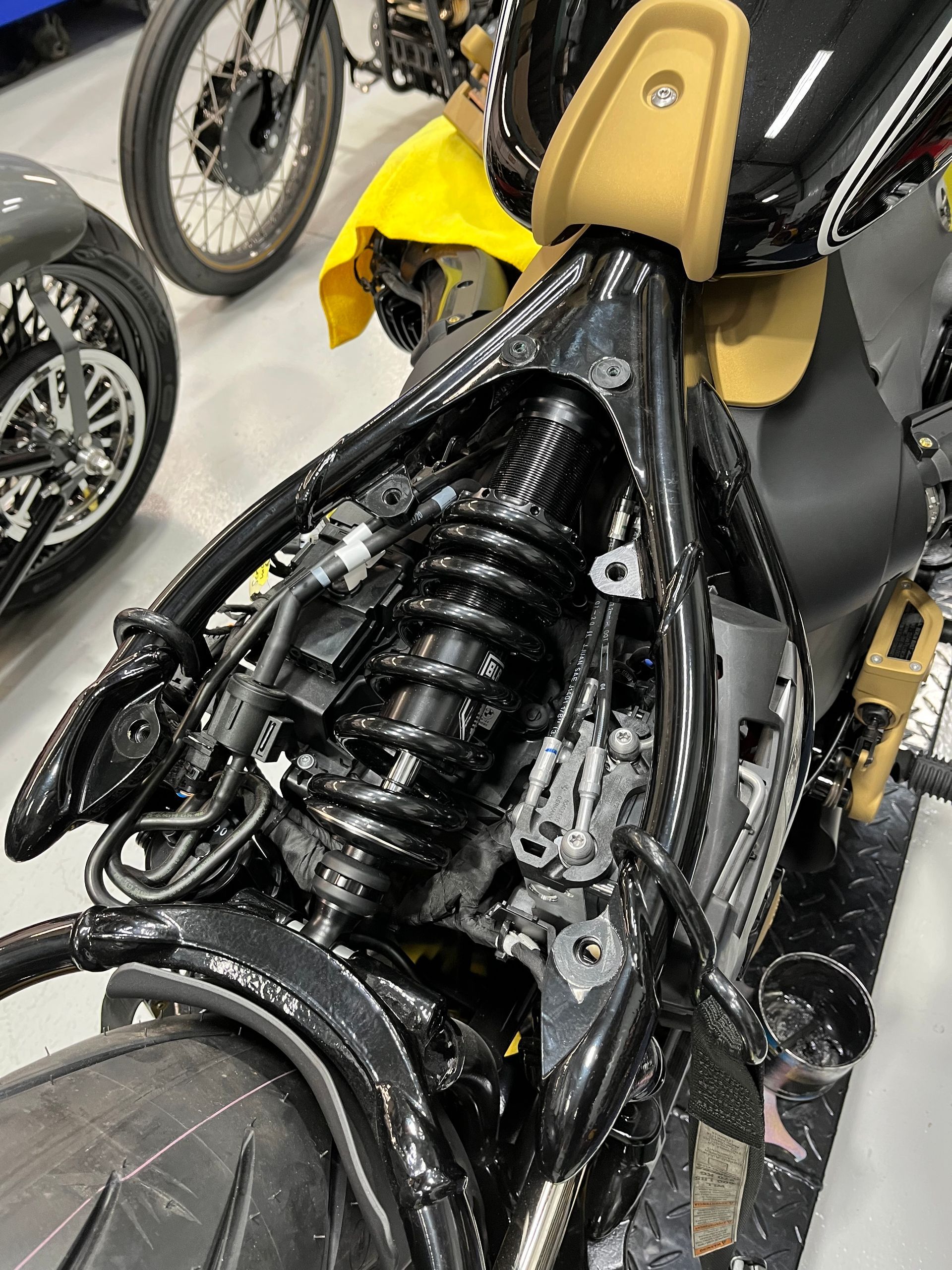 A black motorcycle with a yellow fender is sitting in a garage.