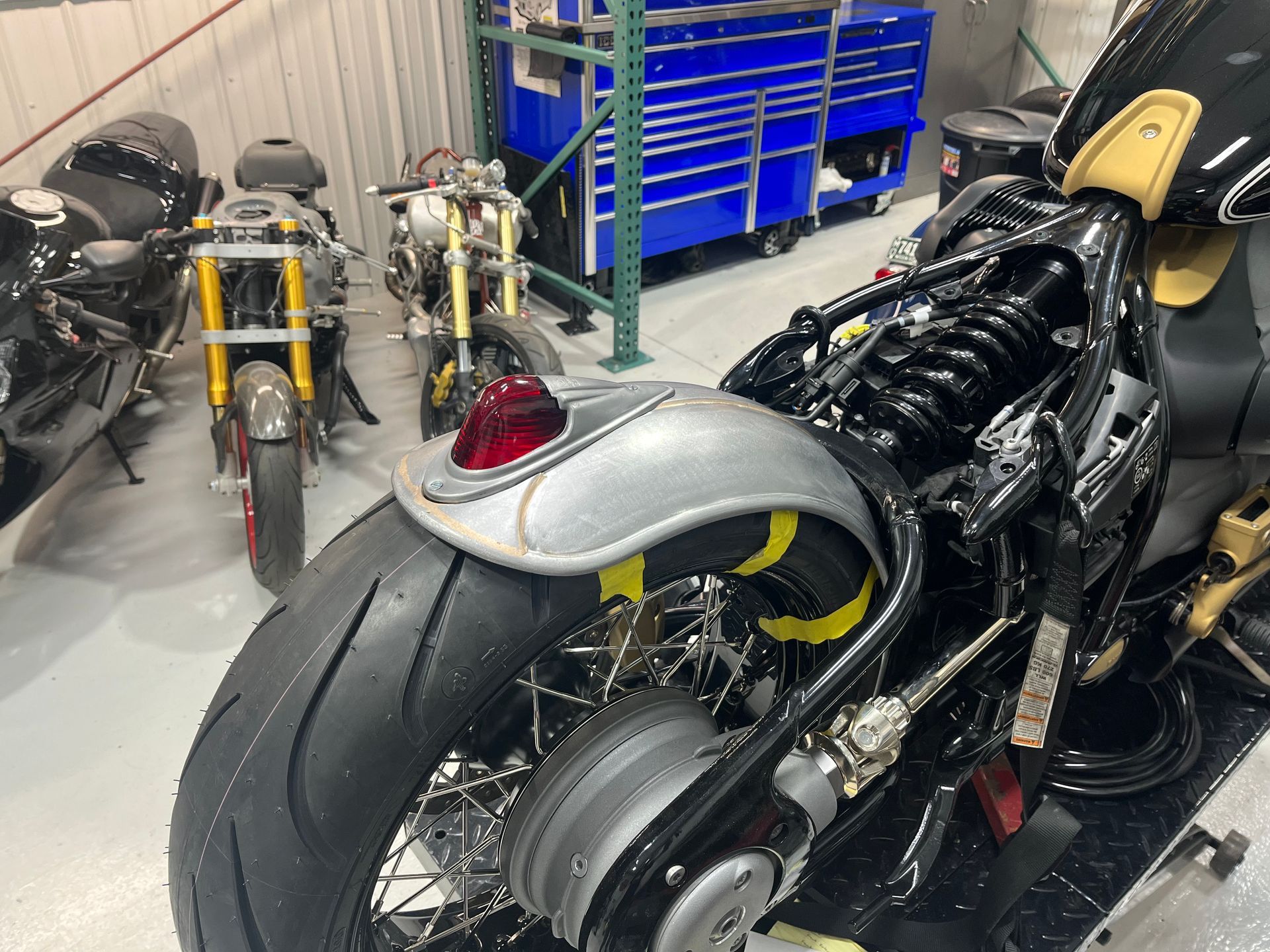 A motorcycle is parked in a garage with other motorcycles.