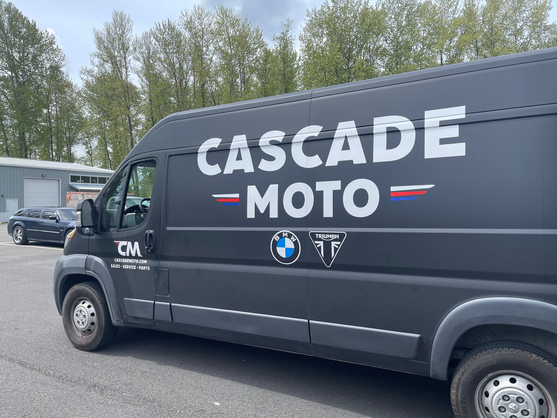 A black van with cascade moto written on the side is parked on the side of the road.