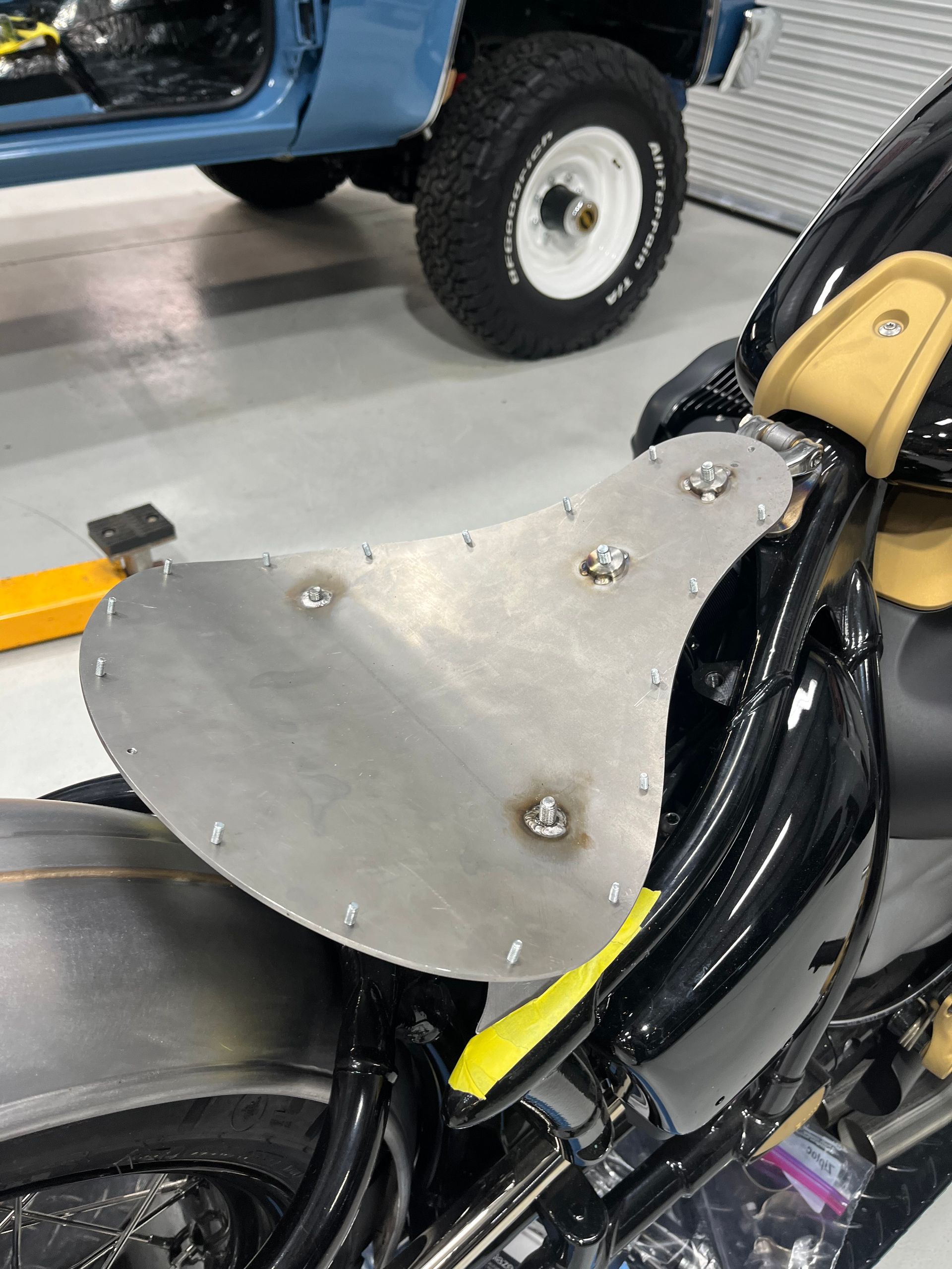 A motorcycle is sitting in a garage next to a blue truck.