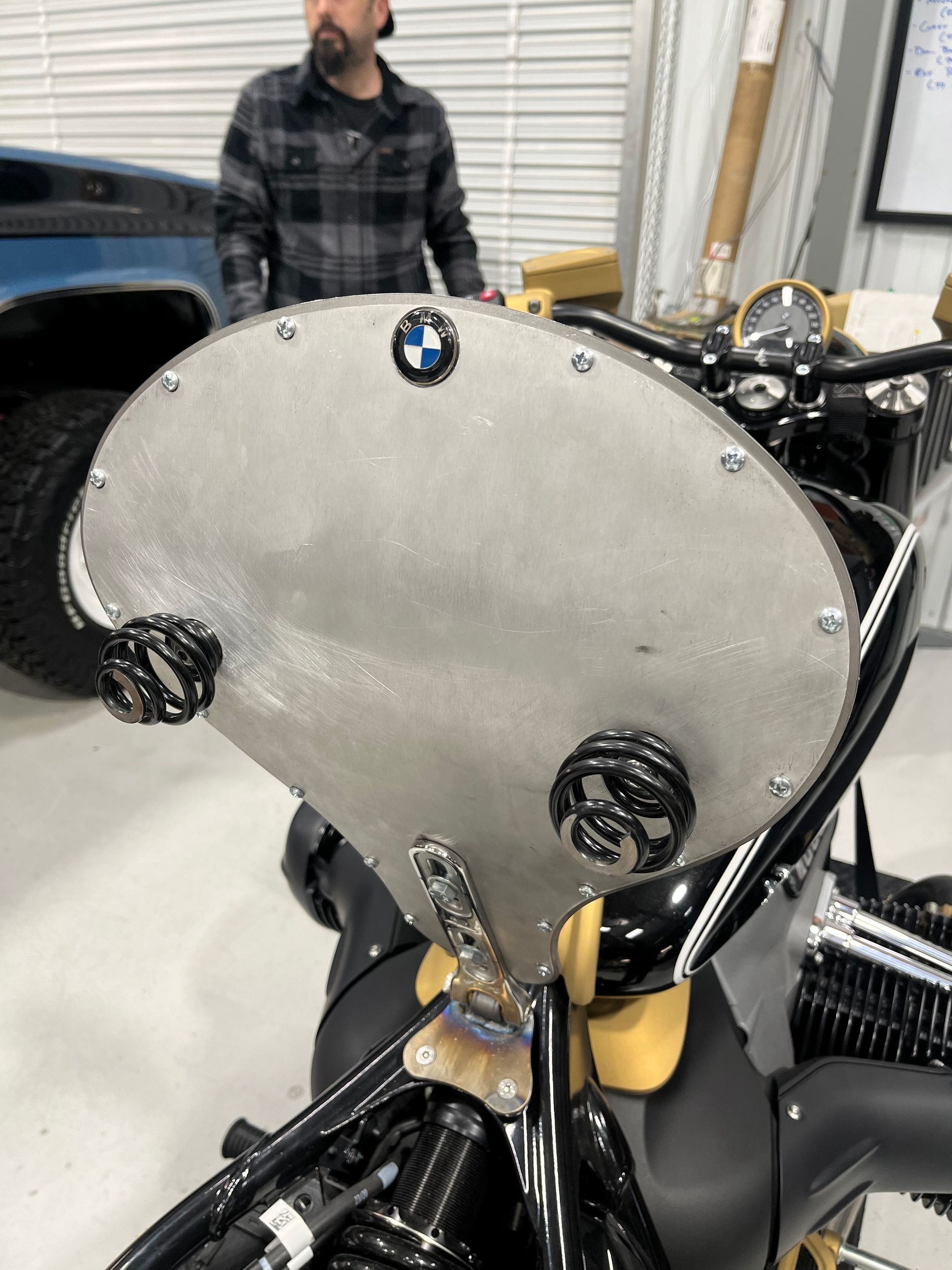 A man is standing next to a motorcycle in a garage.