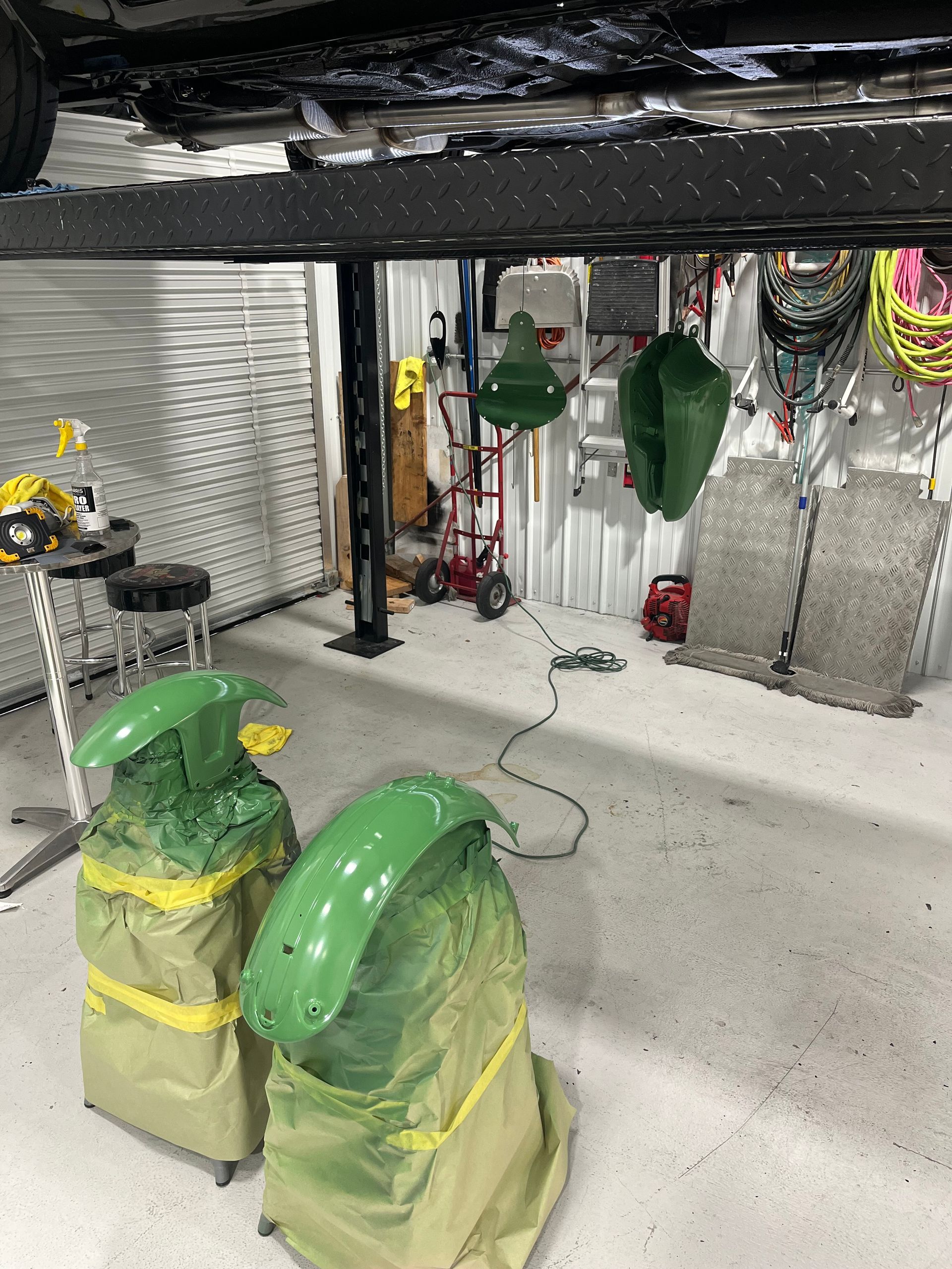 A car is being painted in a garage with green fenders