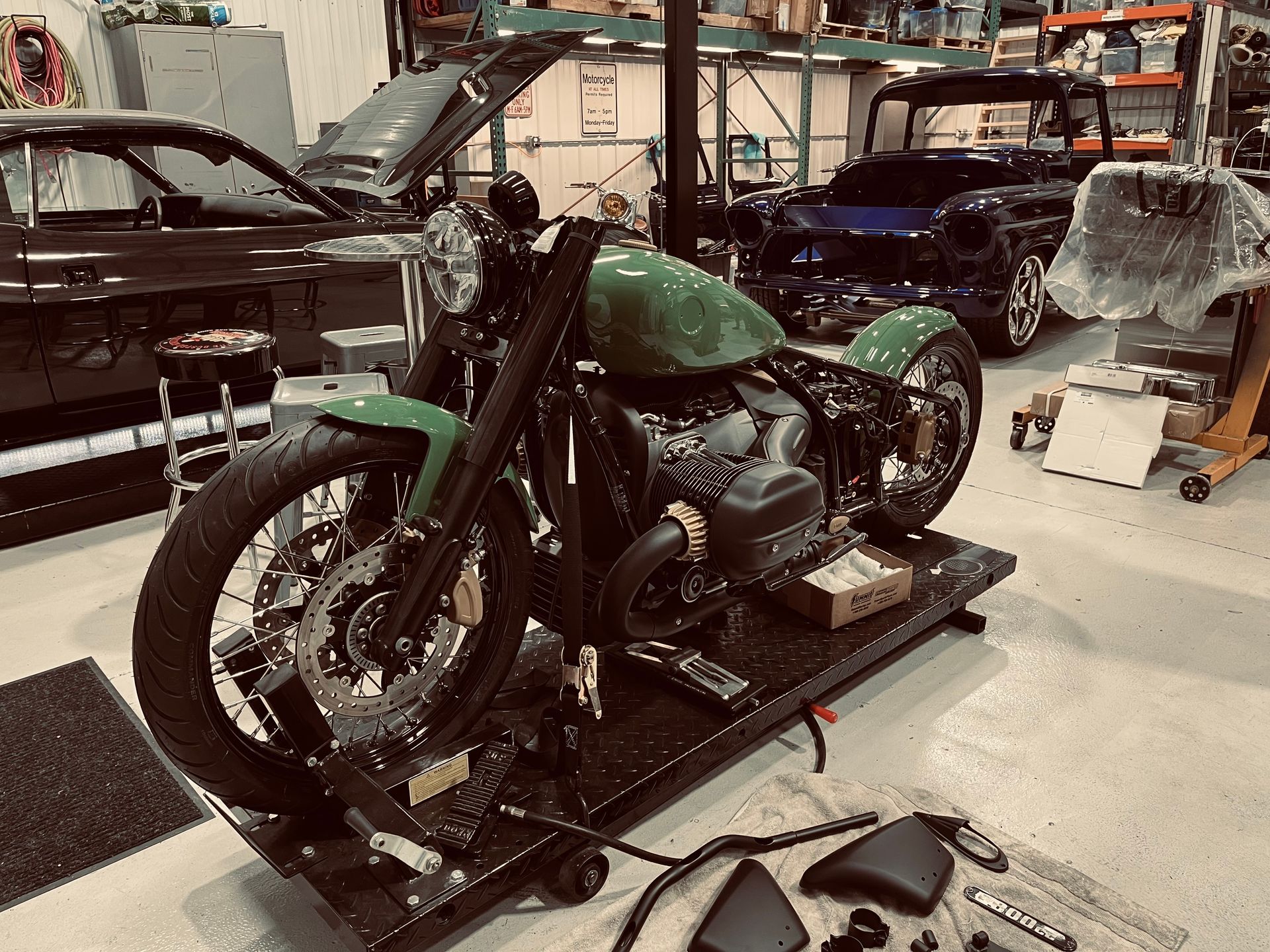 A green motorcycle is sitting on a lift in a garage.
