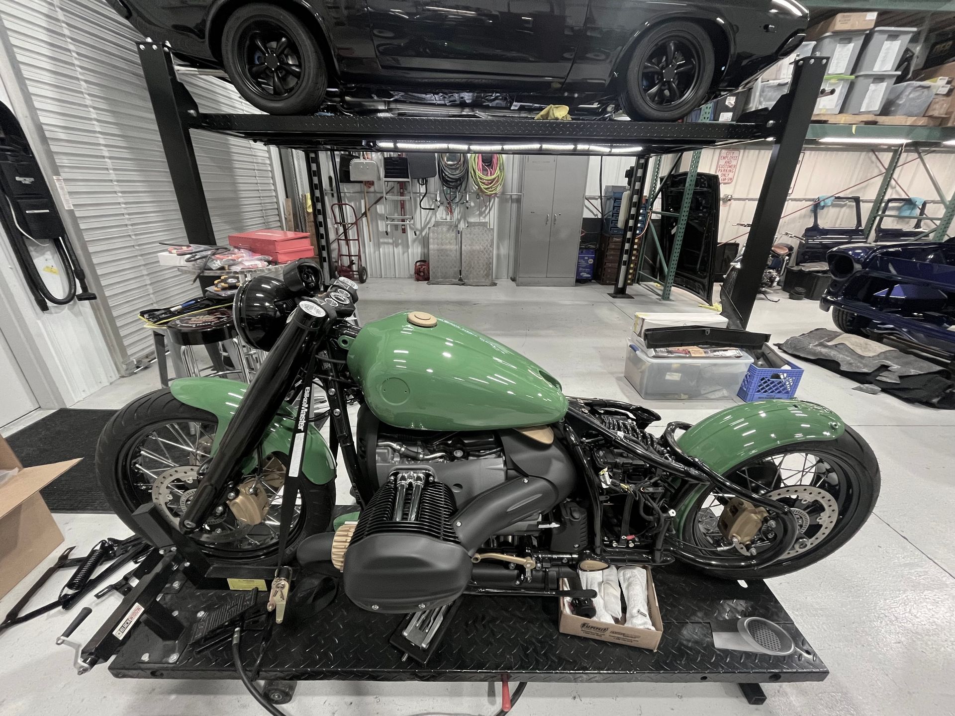 A green motorcycle is sitting on a table in a garage.