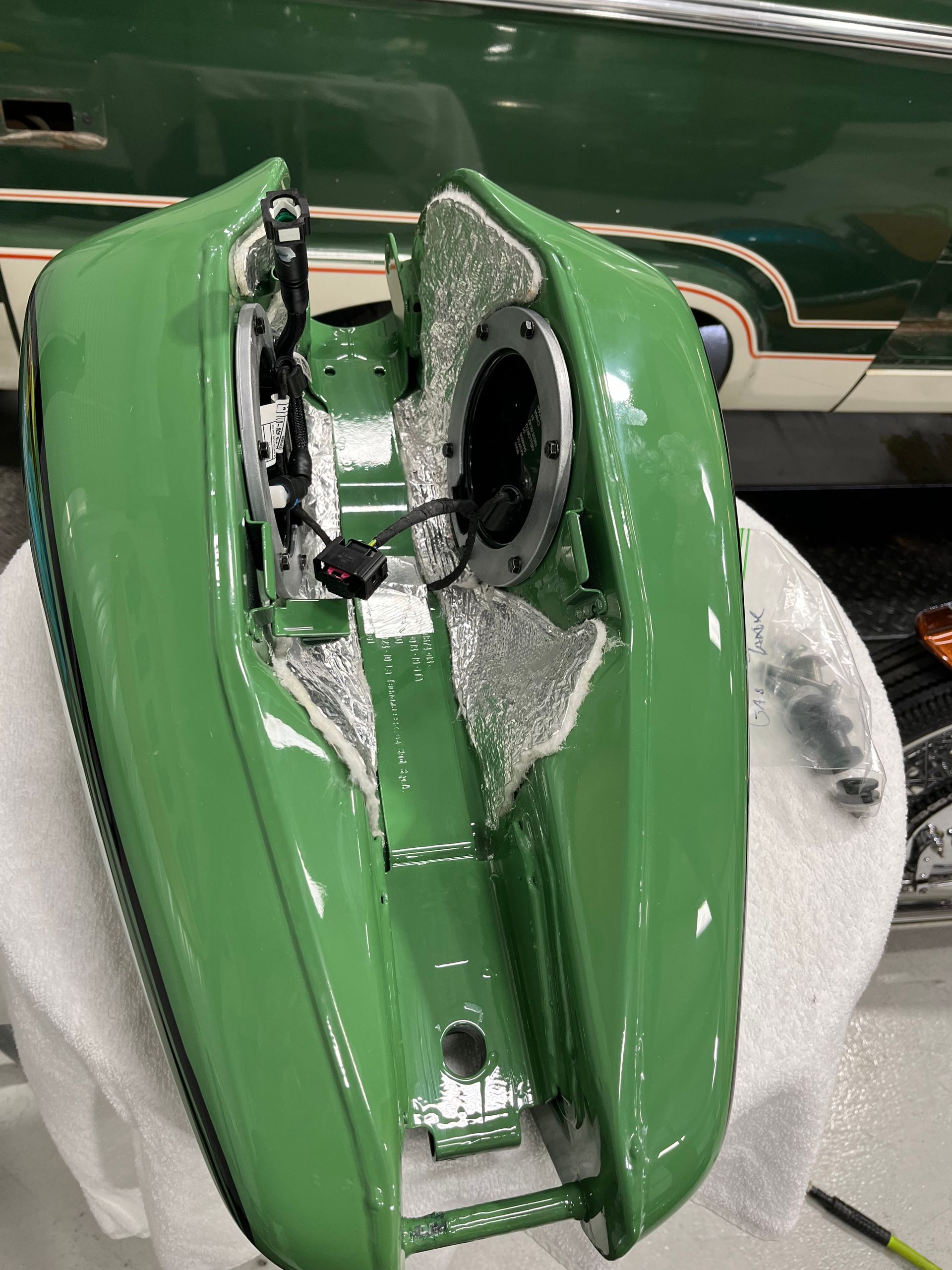 A green motorcycle gas tank is sitting on a white towel.