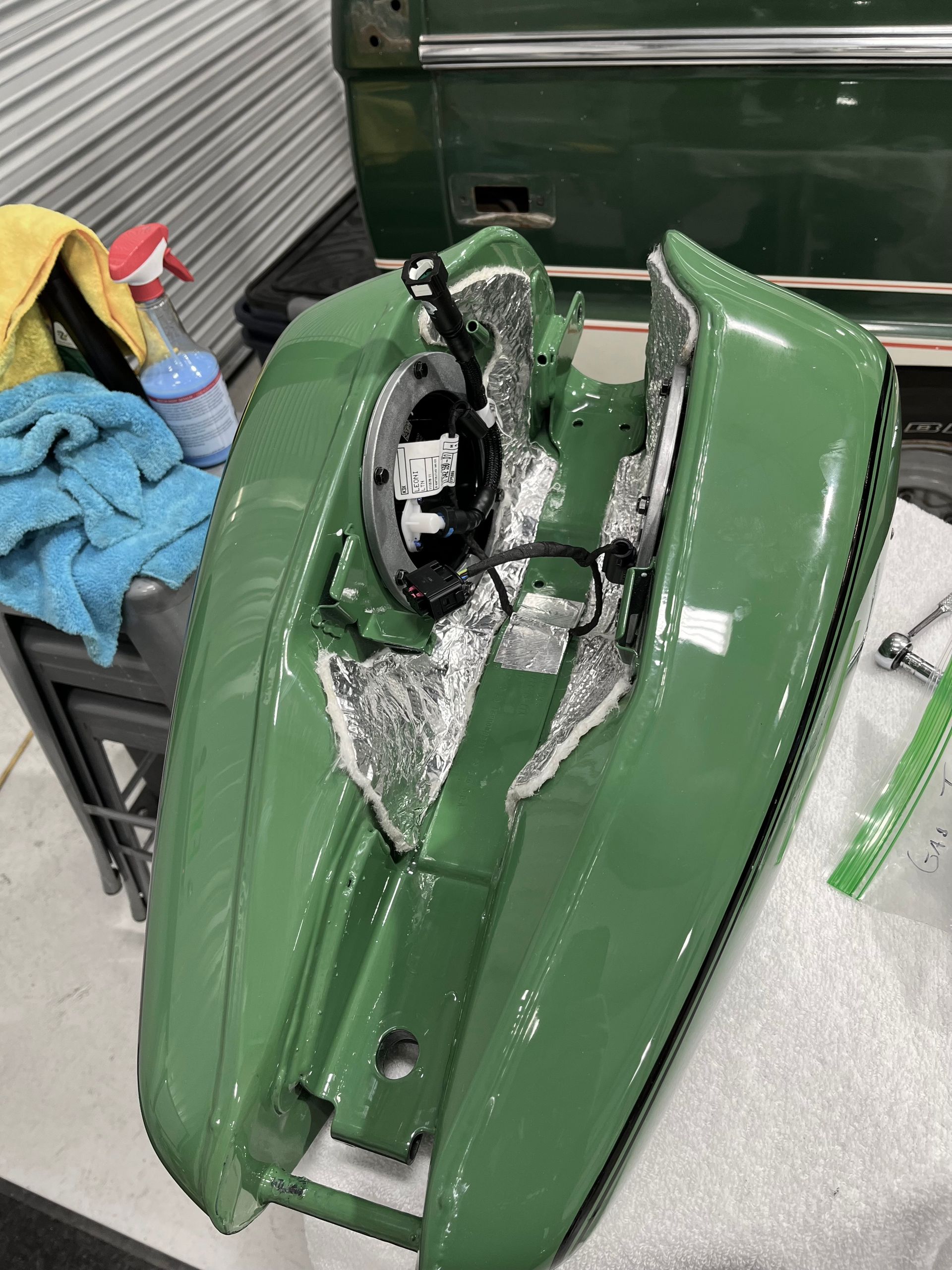 A green motorcycle is sitting on a table in a garage.