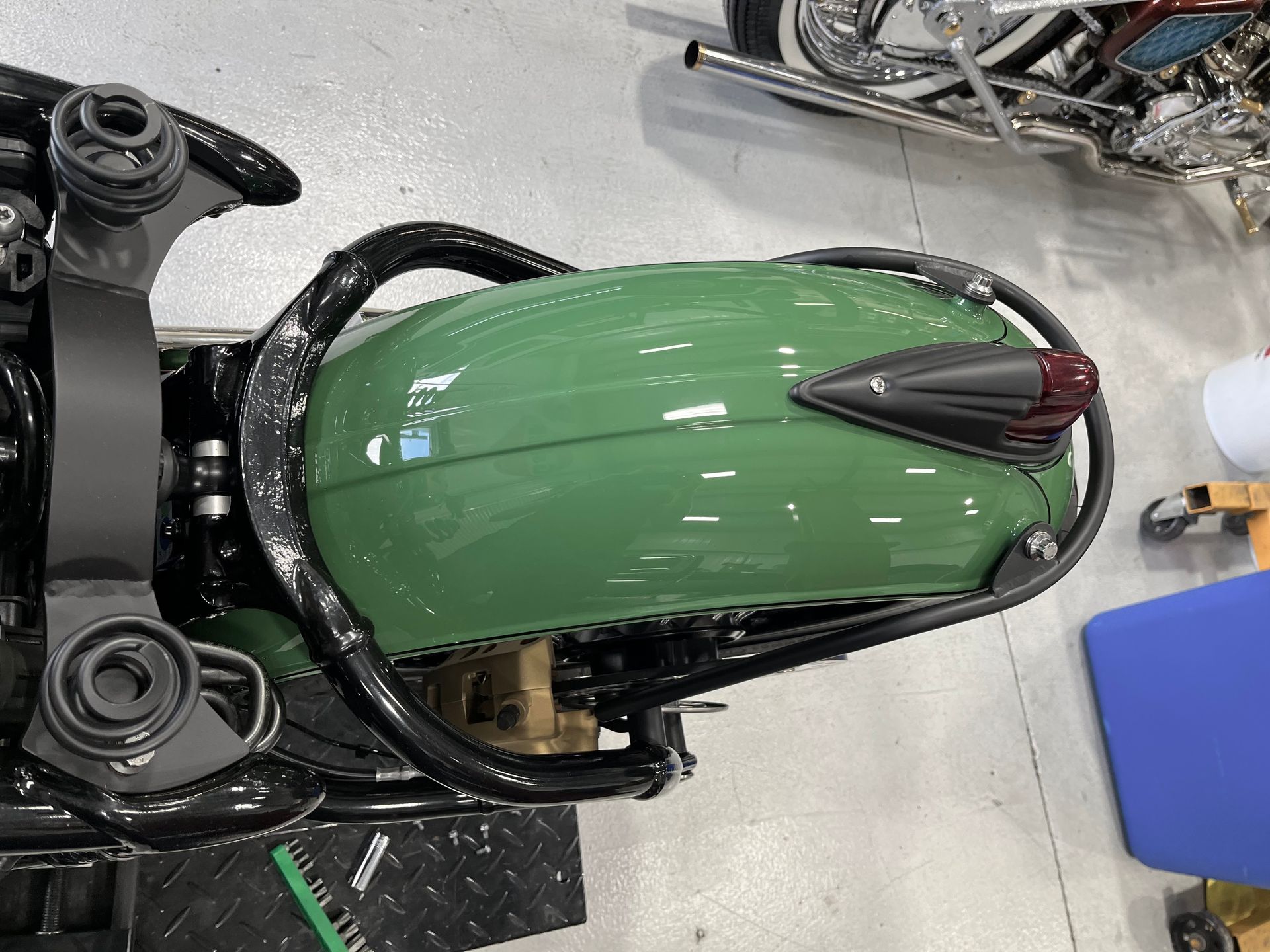 A green motorcycle is parked in a garage next to another motorcycle.