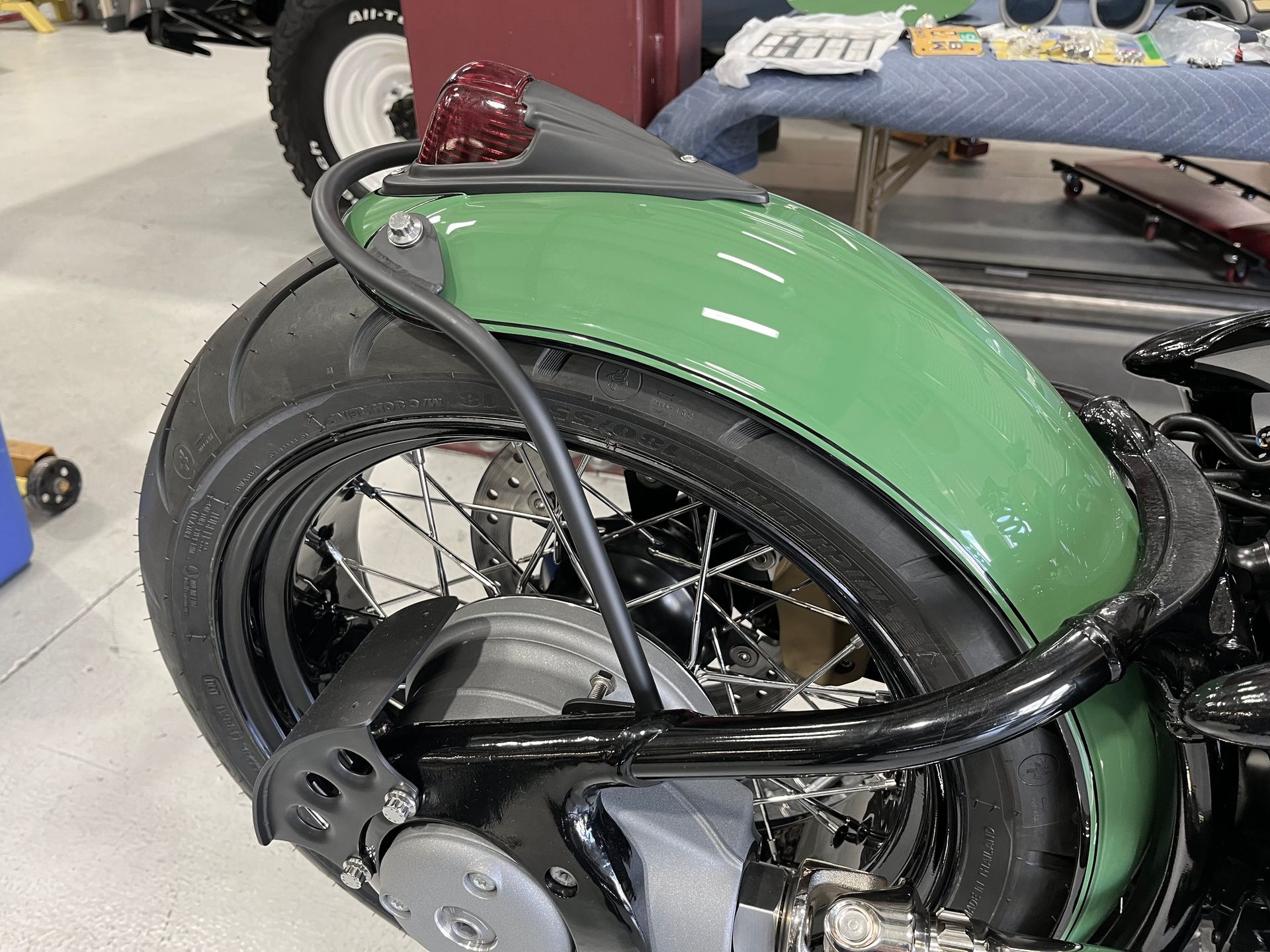 A green motorcycle with a black fender is parked in a garage.