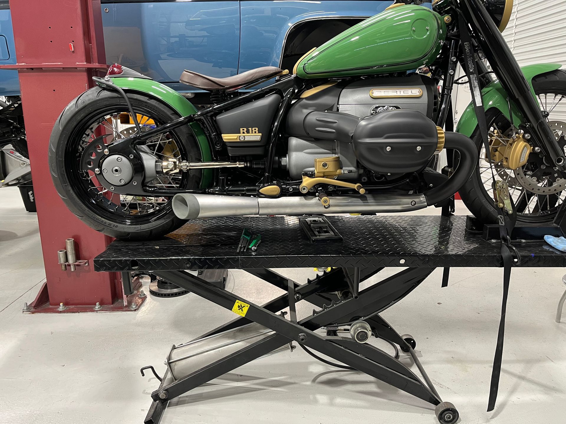 A green motorcycle is sitting on a lift in a garage.