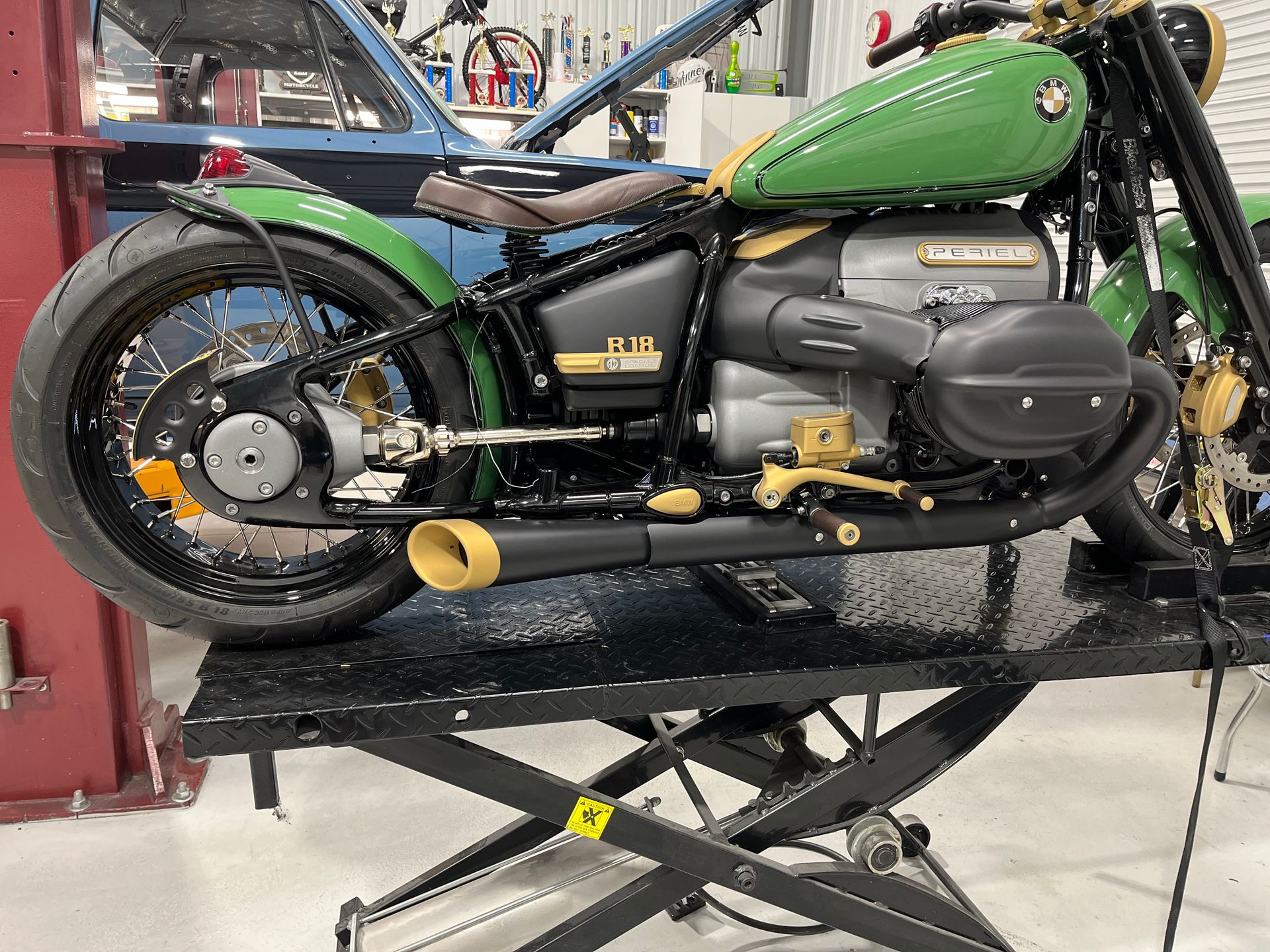 A green motorcycle is sitting on a lift in a garage.