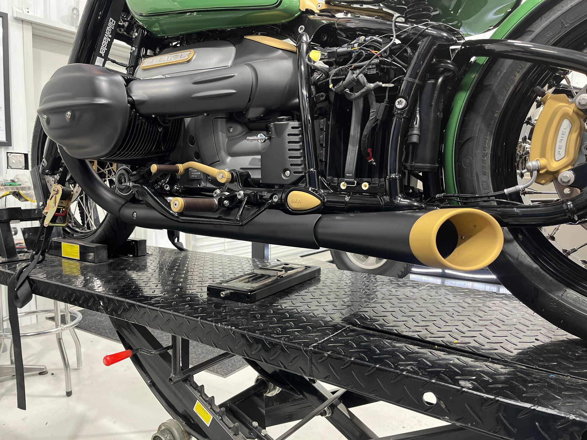 A green motorcycle is sitting on top of a black lift.