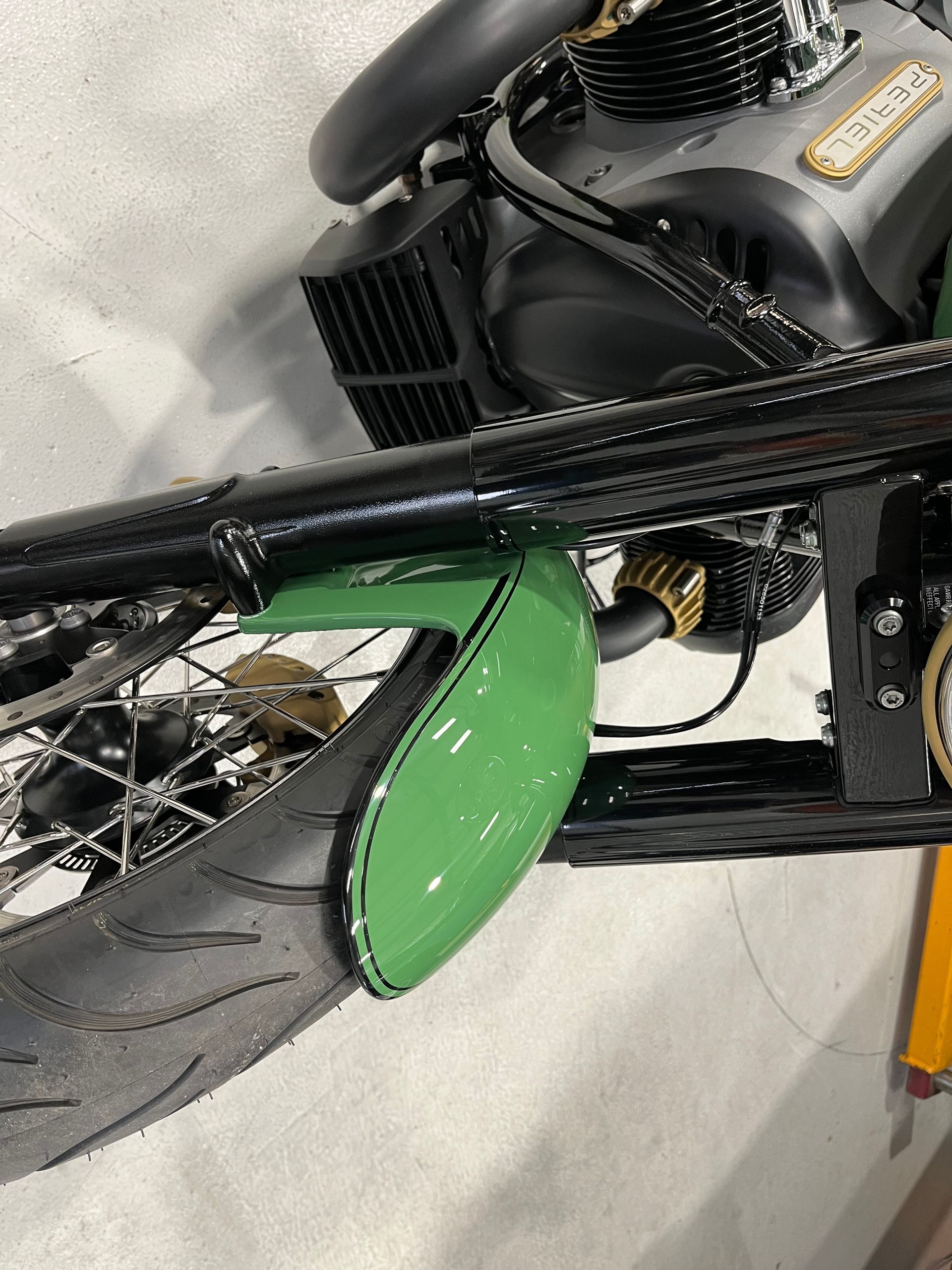 A close up of a motorcycle with a green fender and a black engine.