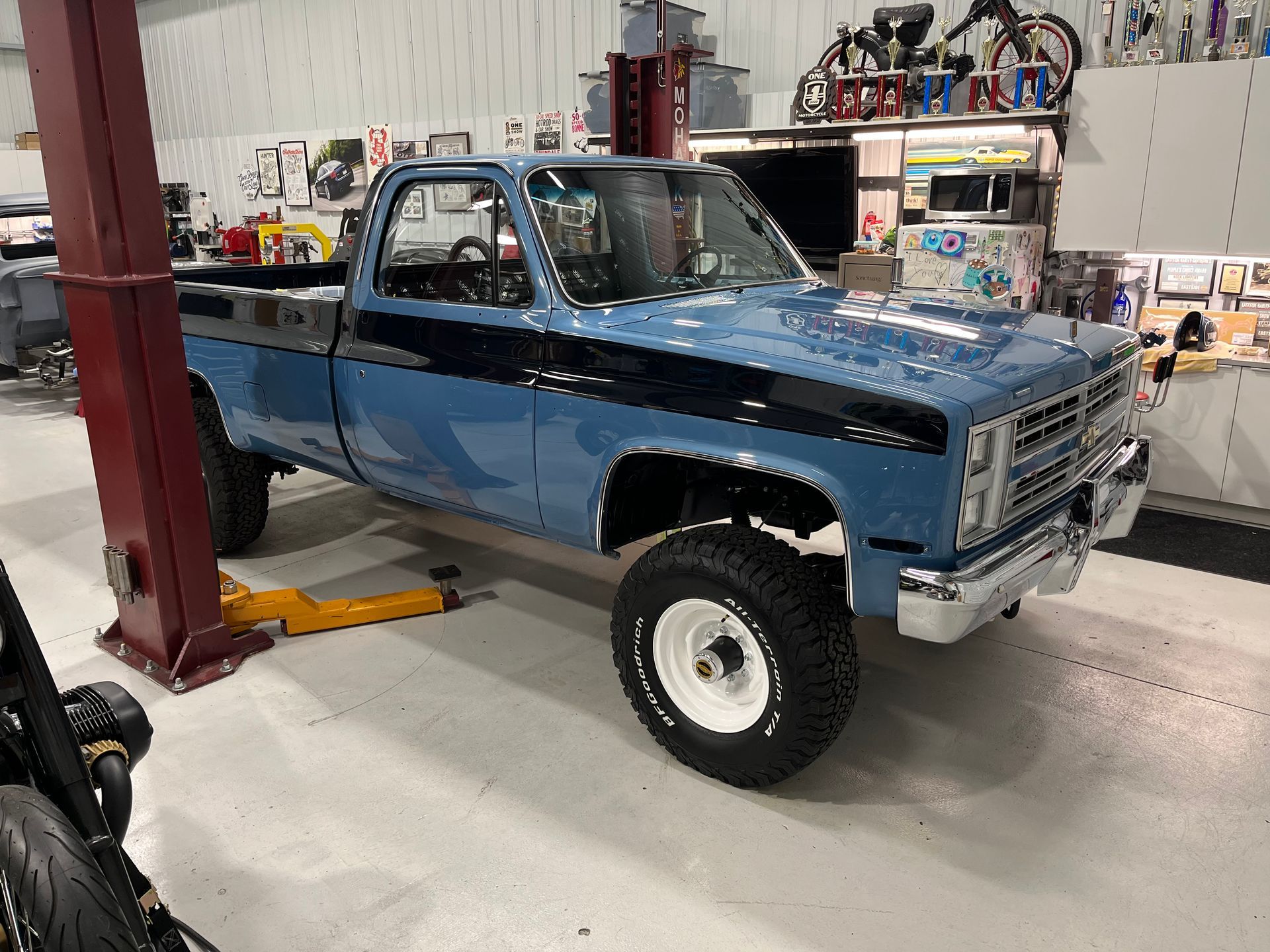 A blue truck is parked on a lift in a garage.