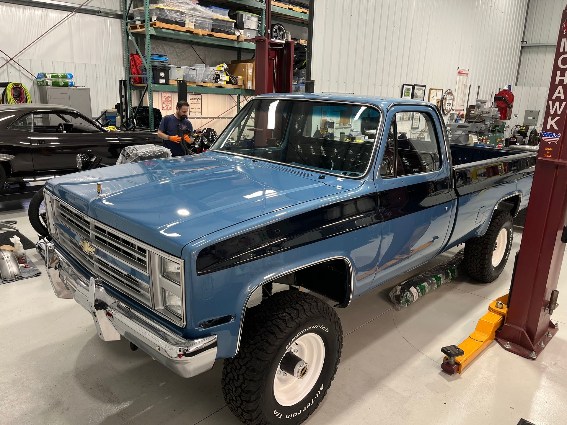 A blue truck is parked on a lift in a garage.