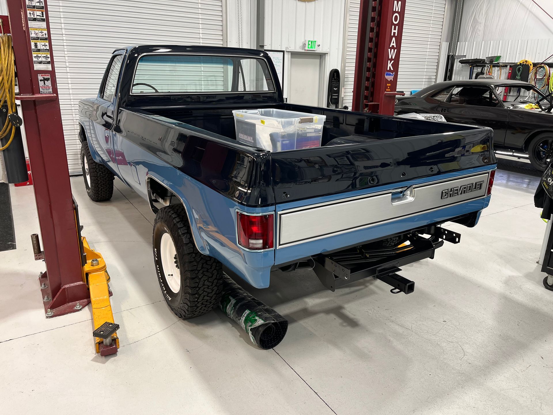 A blue truck is parked in a garage on a lift.