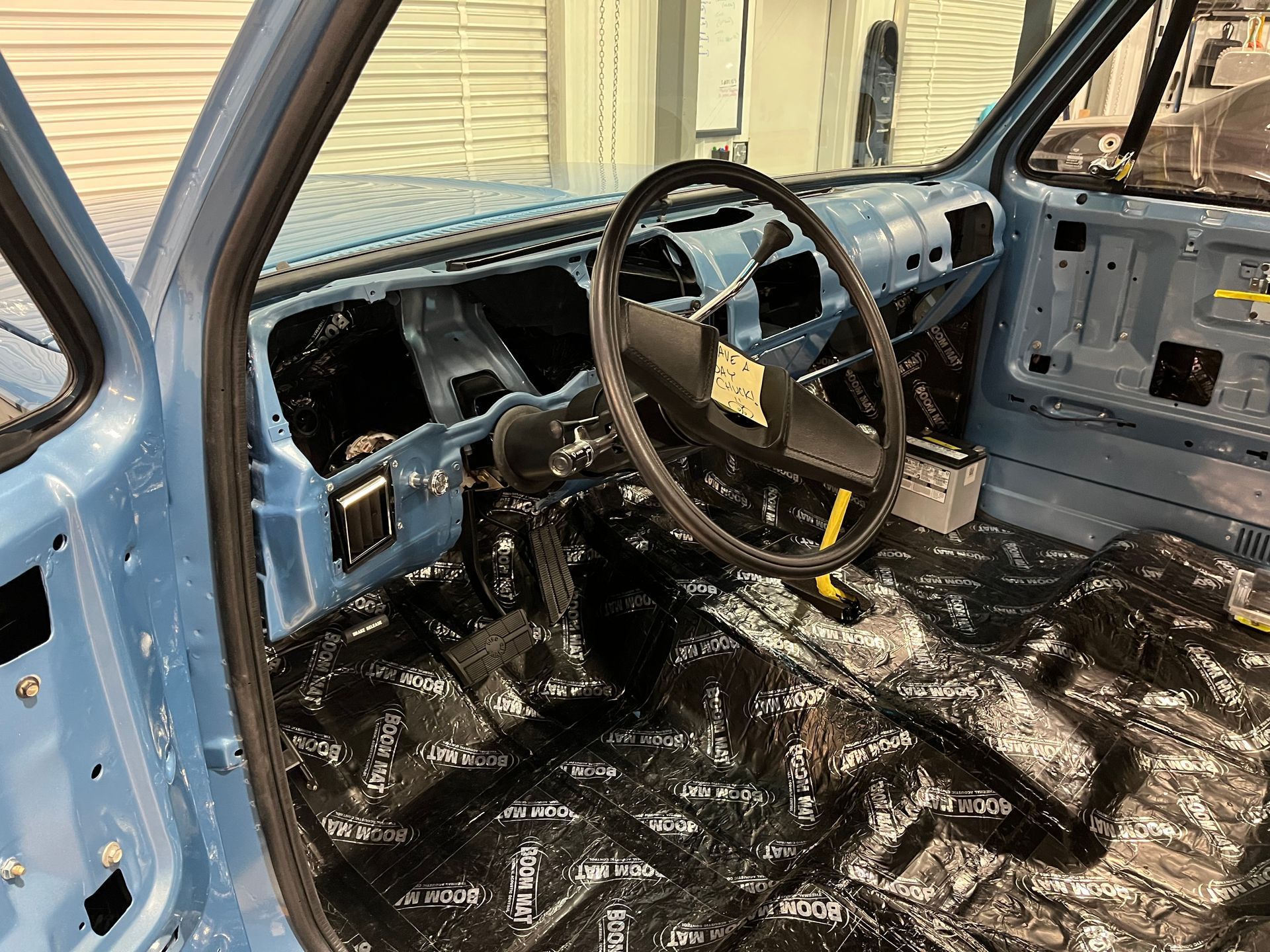 The interior of a blue car is covered in plastic wrap.