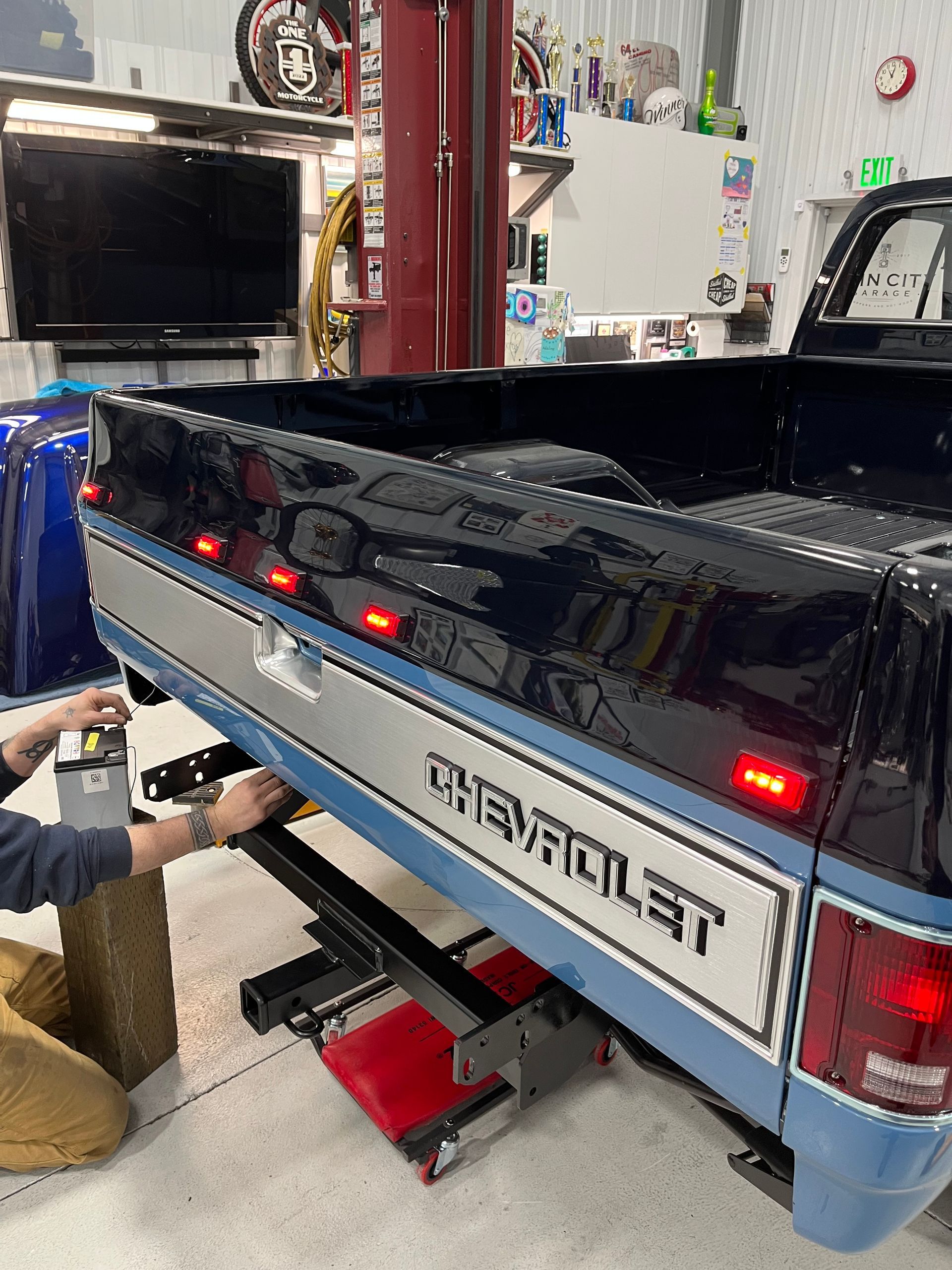 A man is working on a chevrolet truck in a garage.