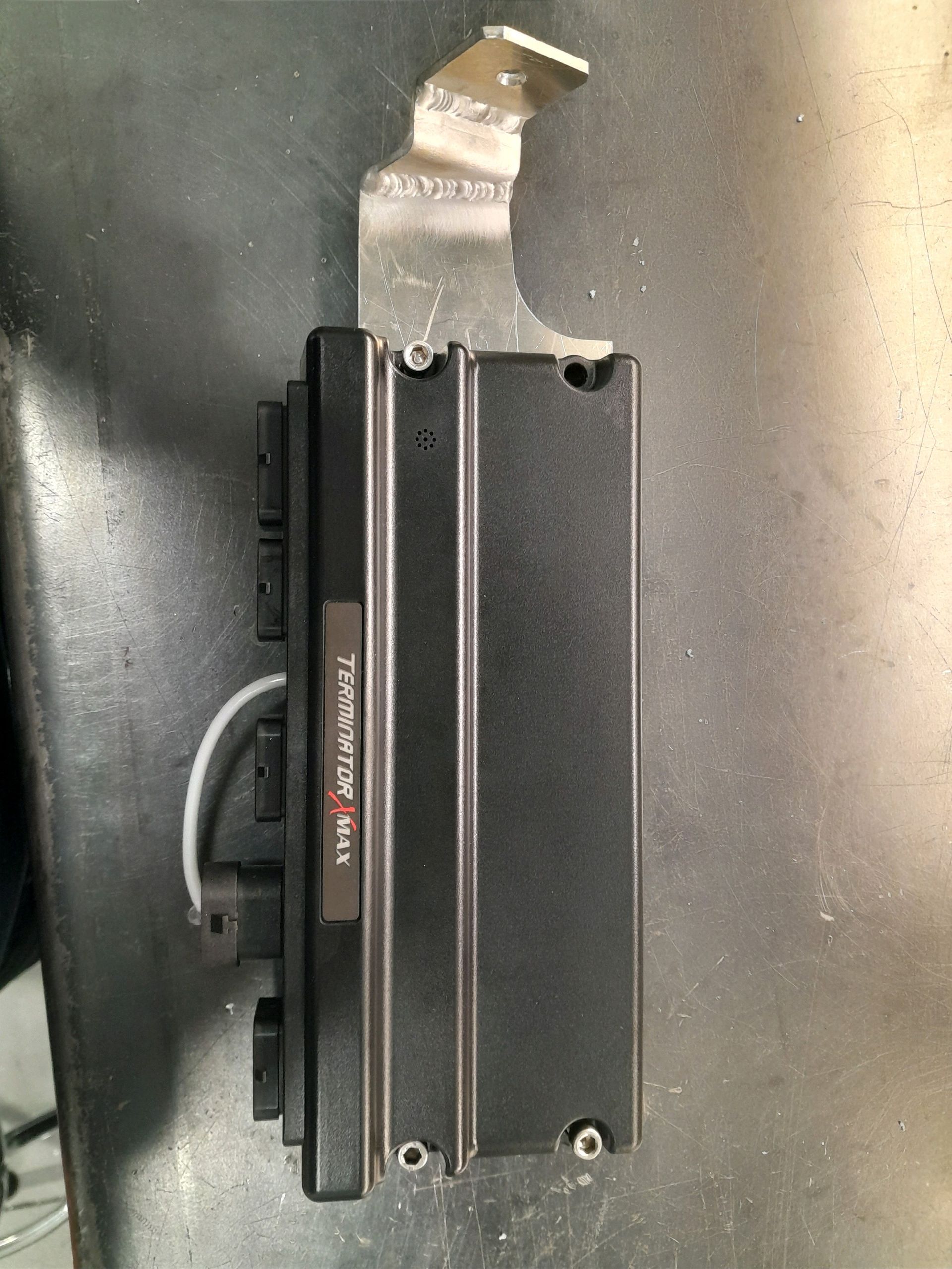 A black device is sitting on a metal surface.