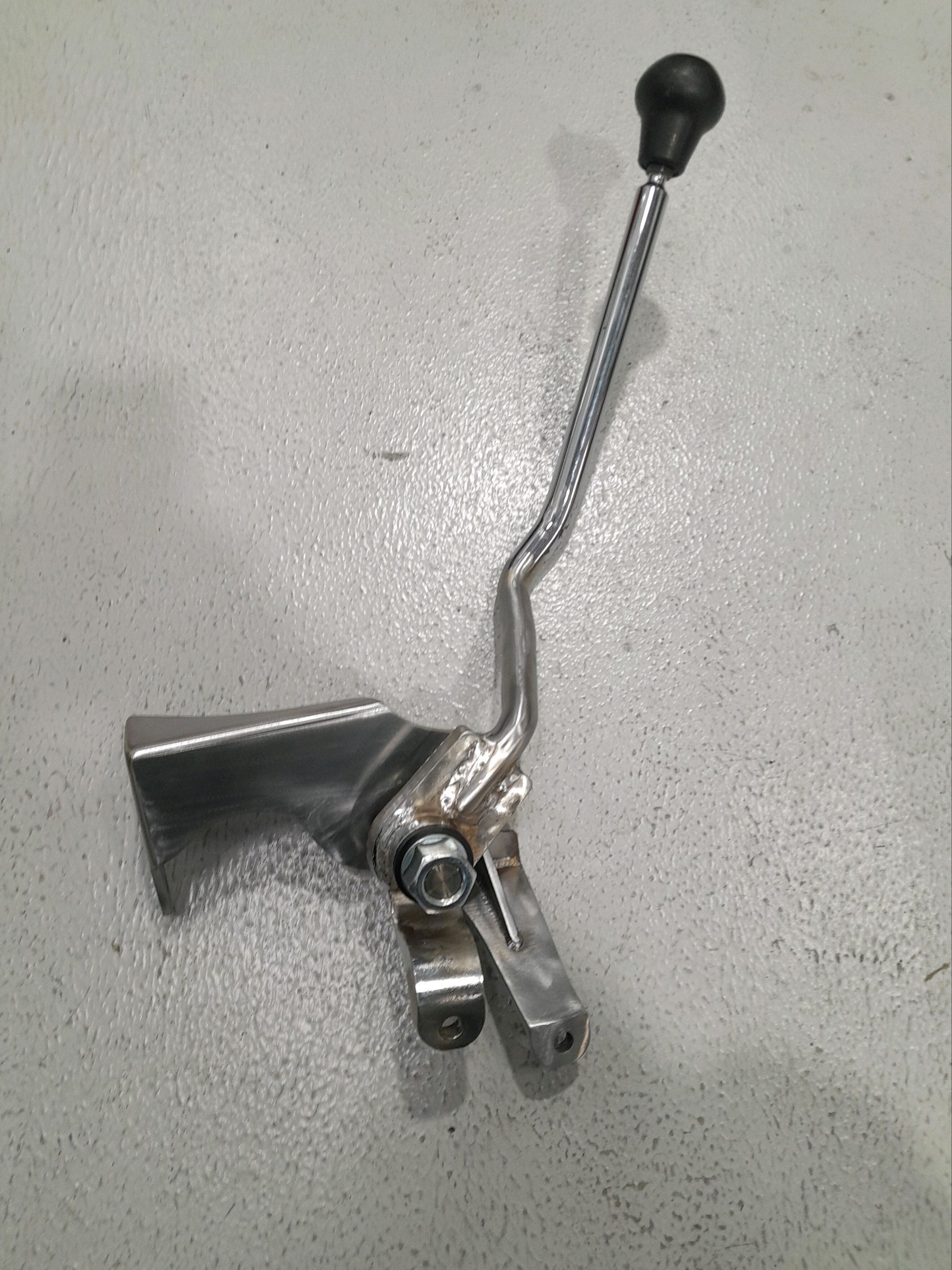 A metal object with a black handle is sitting on a white surface.
