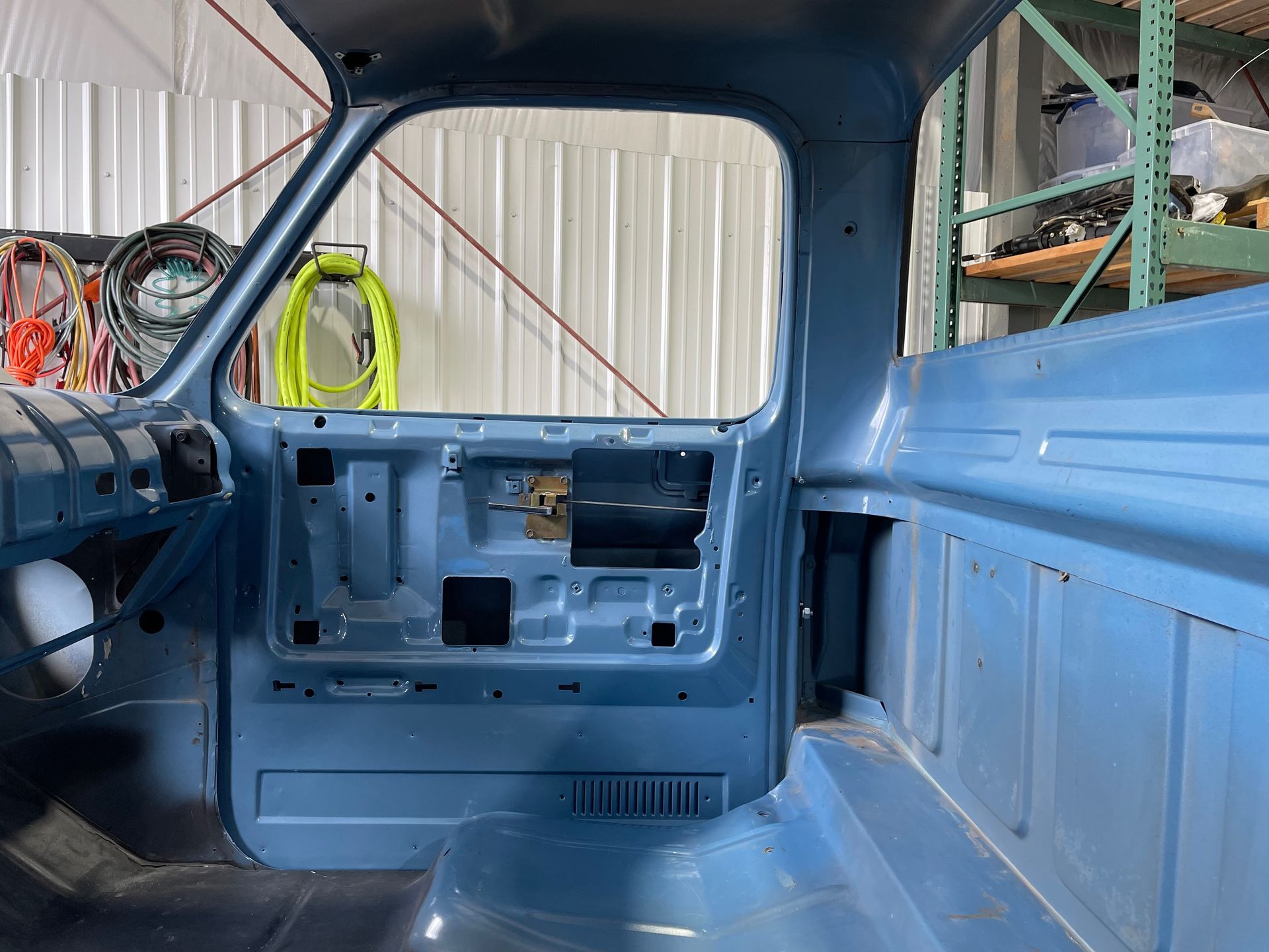 A blue truck is being built in a garage.