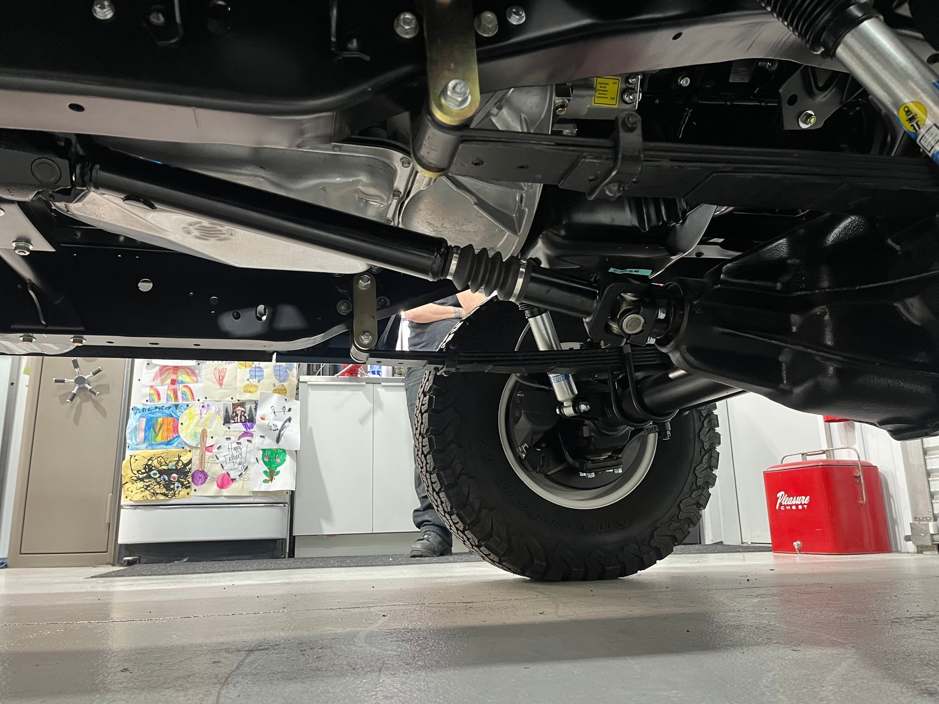 A man is working on the underside of a car in a garage.