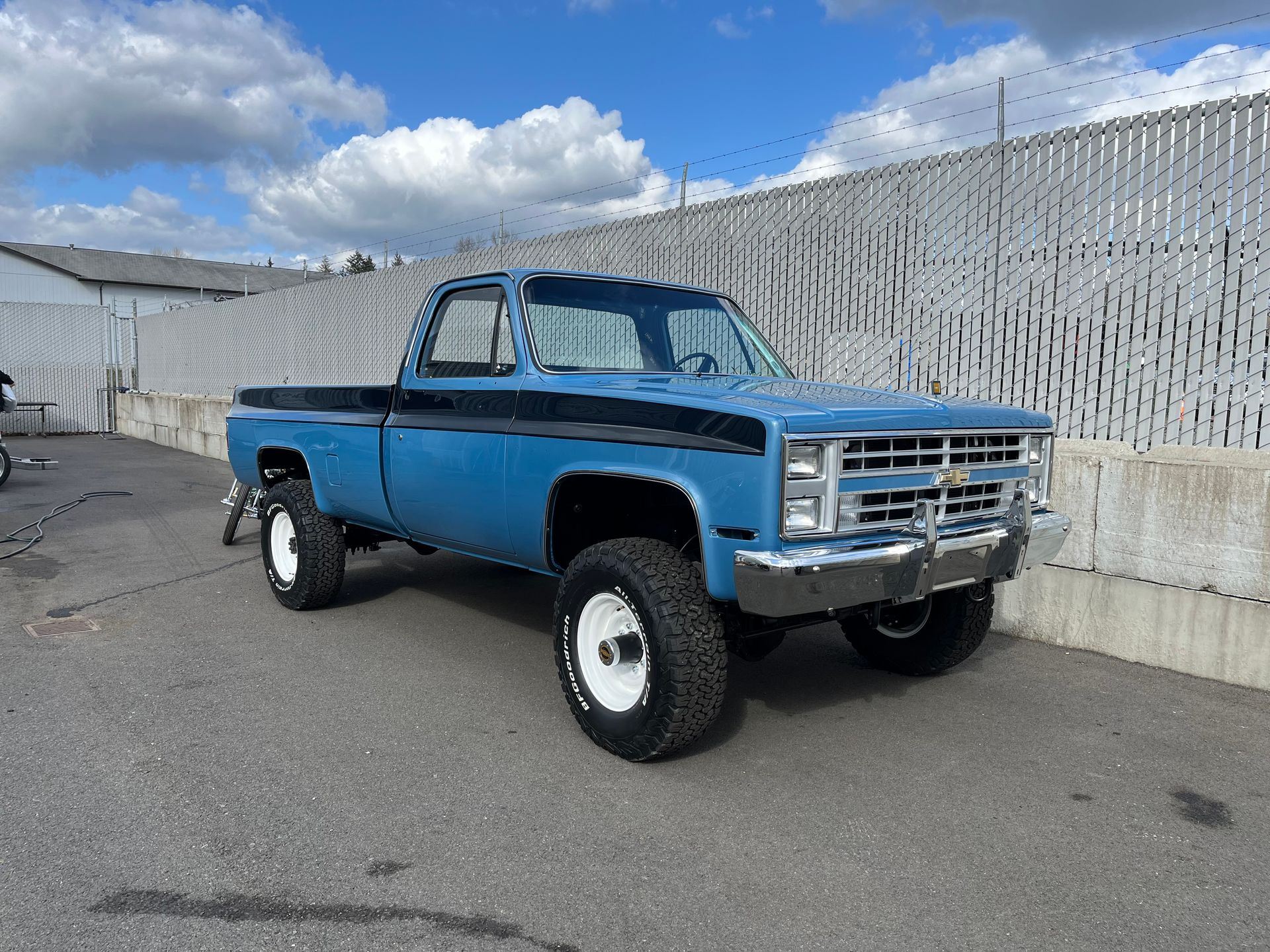 A blue truck is parked in front of a fence.