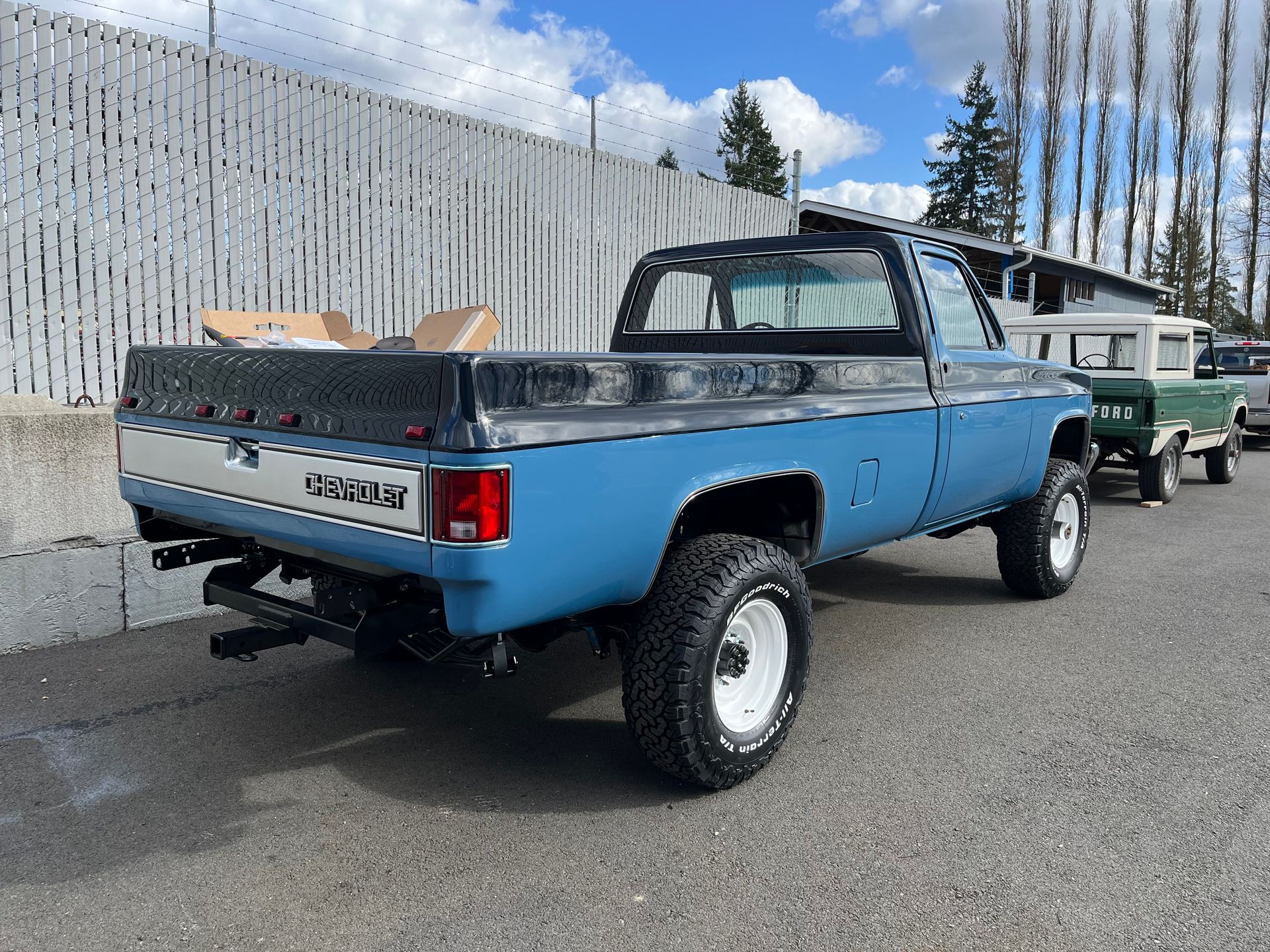A blue truck is parked in front of a fence.