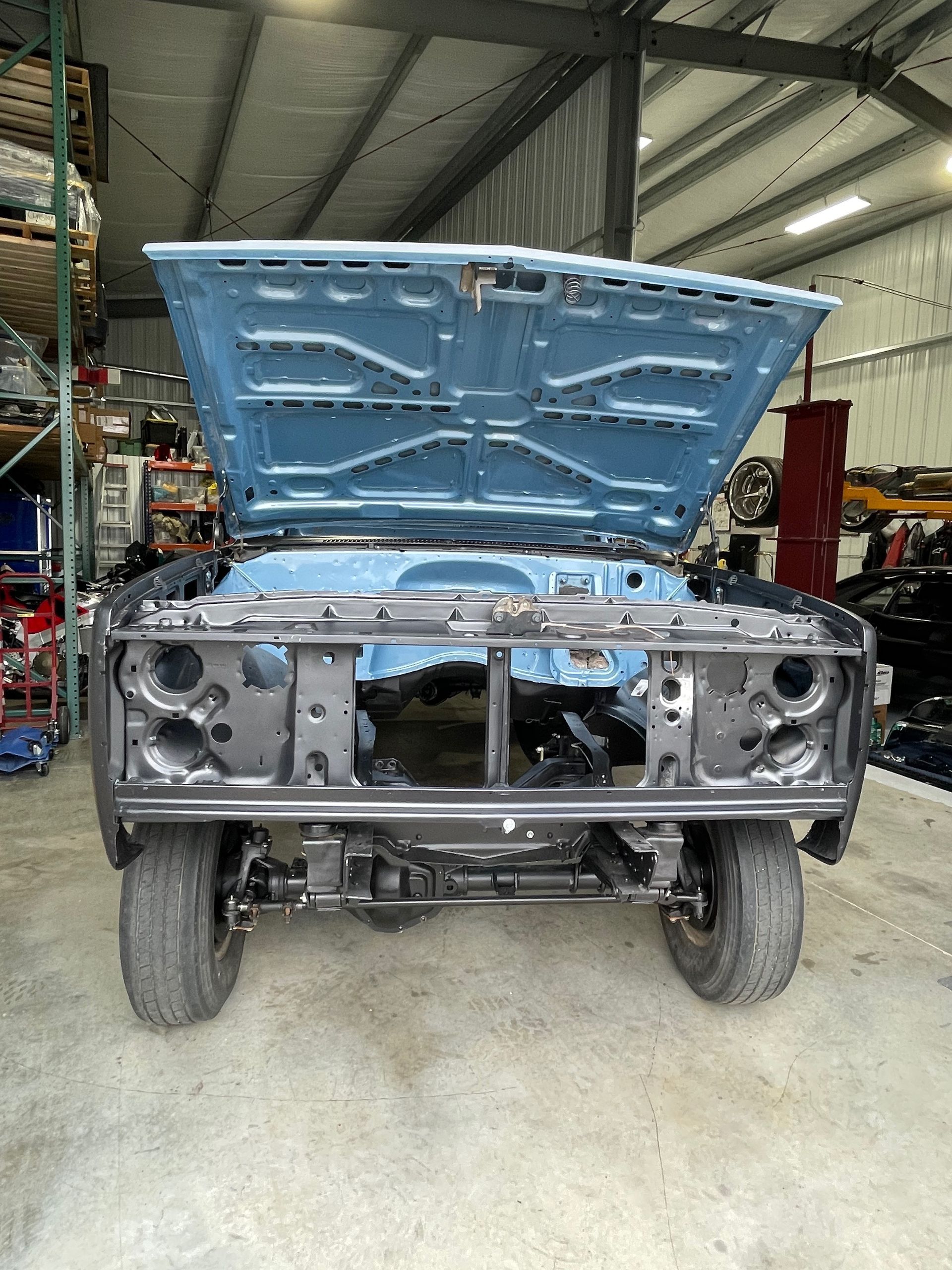 A car with the hood open is sitting in a garage.
