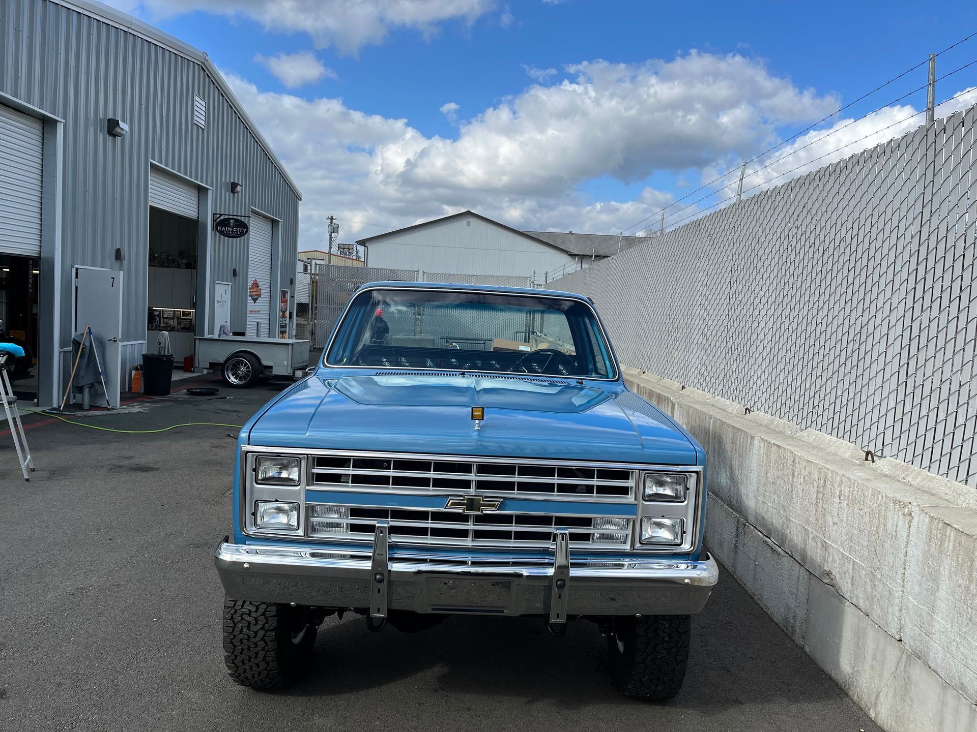 A blue truck is parked in front of a building.