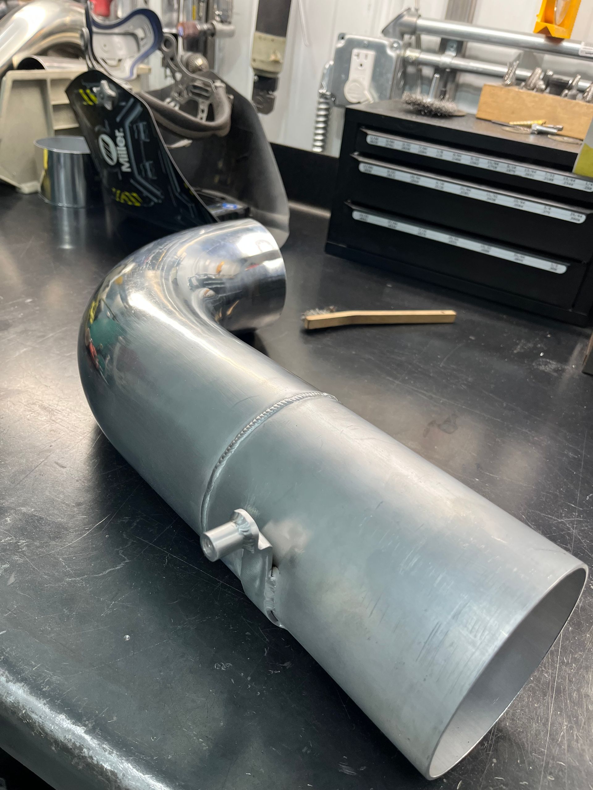 A metal pipe is sitting on a table next to a toolbox.