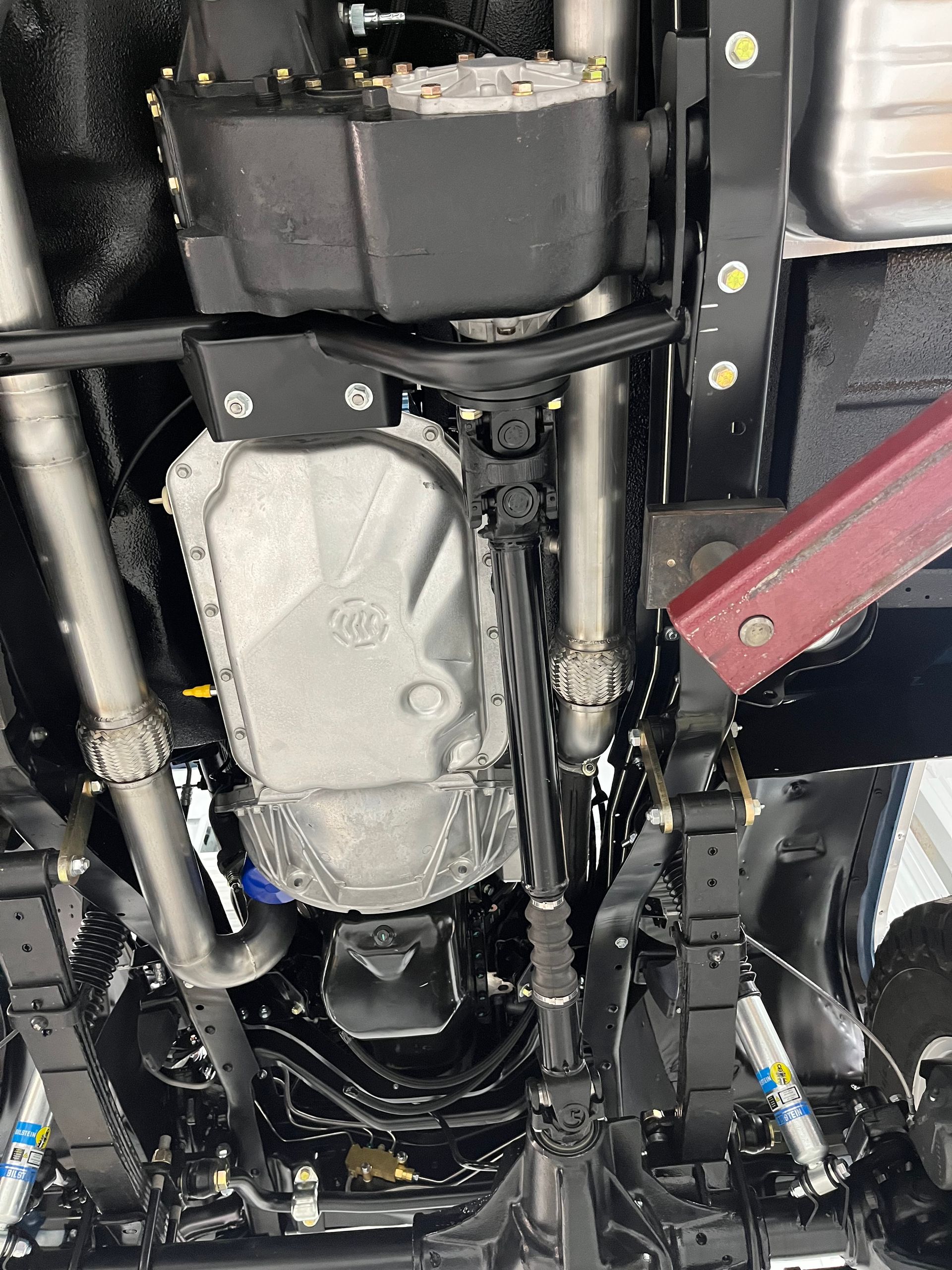 A close up of the underside of a car showing the engine and exhaust pipes.
