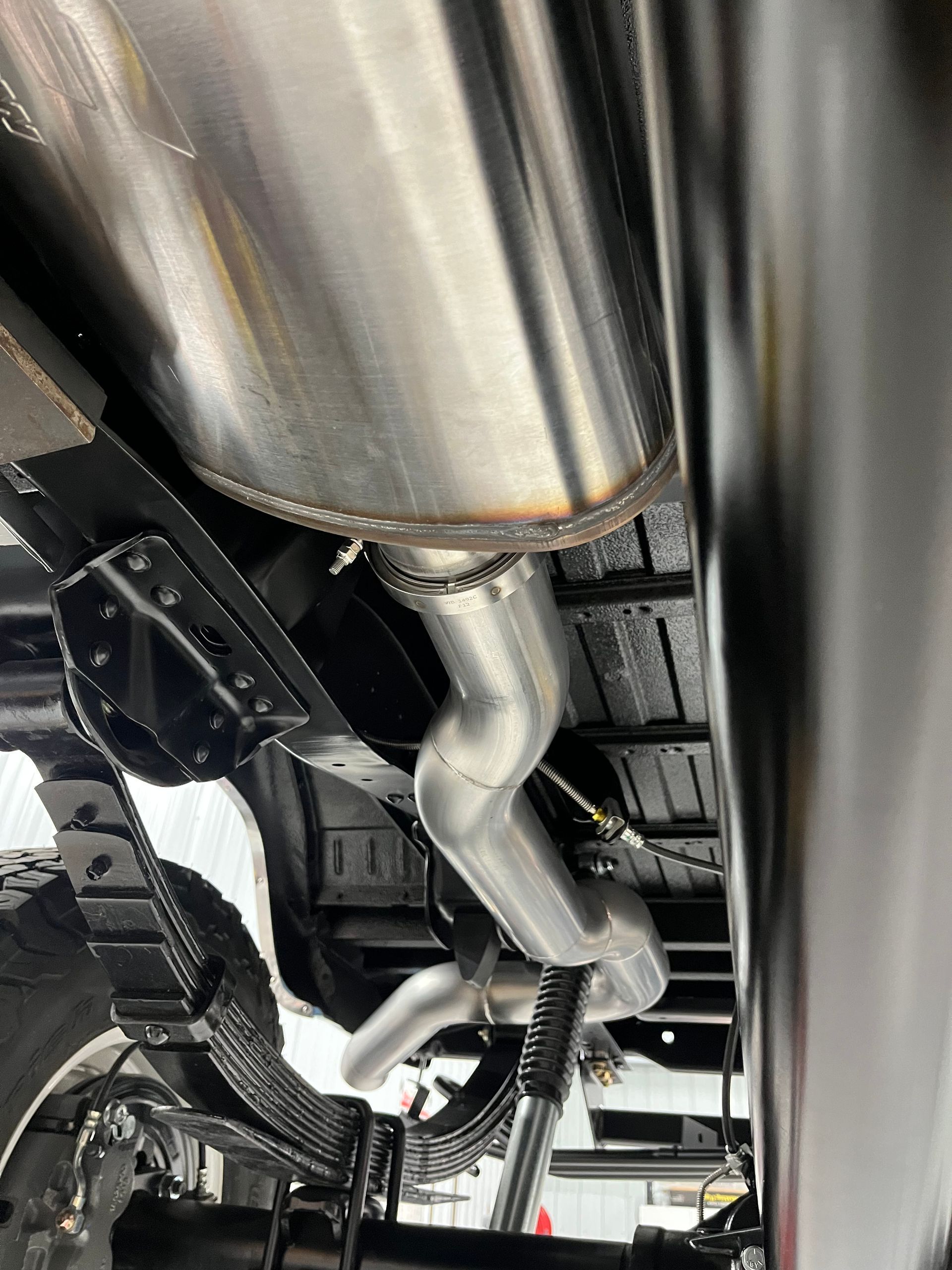 A close up of a stainless steel exhaust pipe on the underside of a truck.