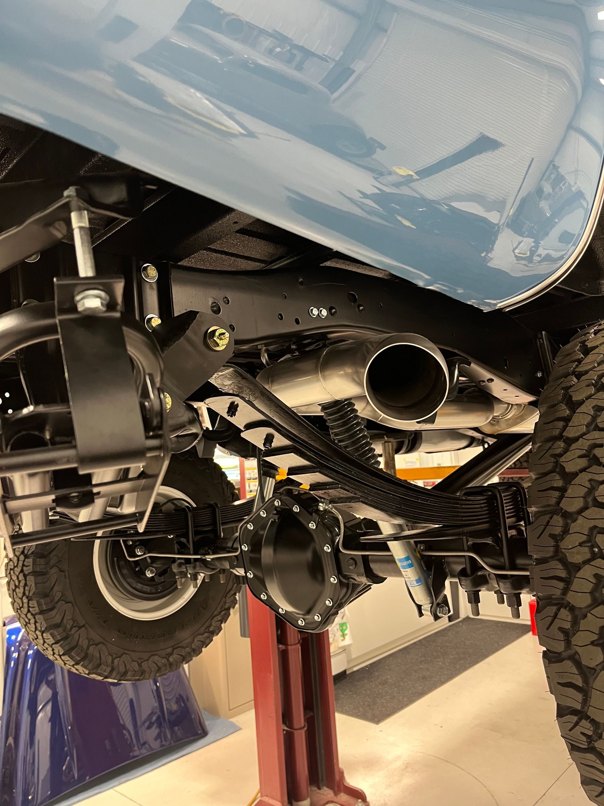 A blue truck is sitting on a lift in a garage.