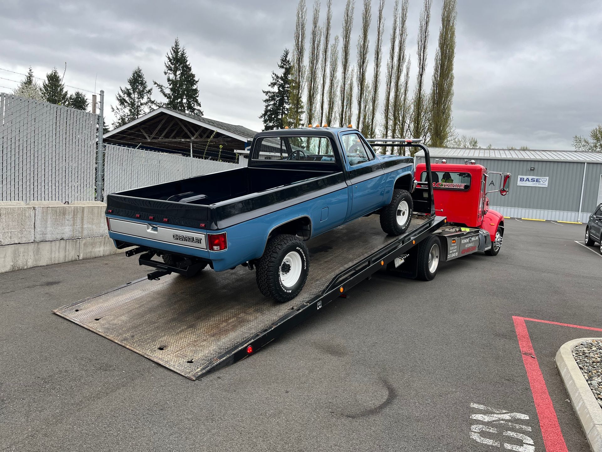A blue truck is being towed by a red tow truck.