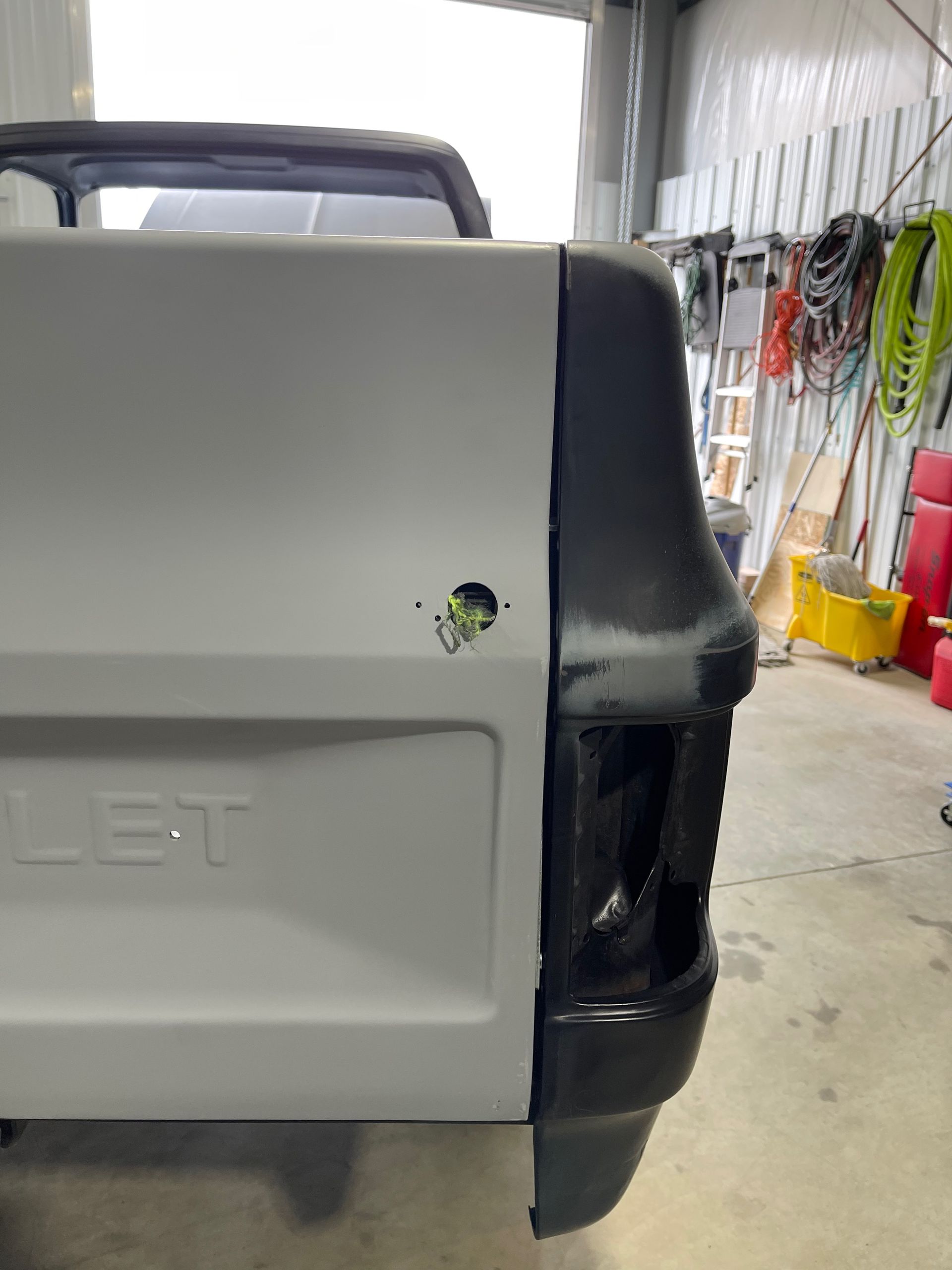 The back of a white truck is sitting in a garage.