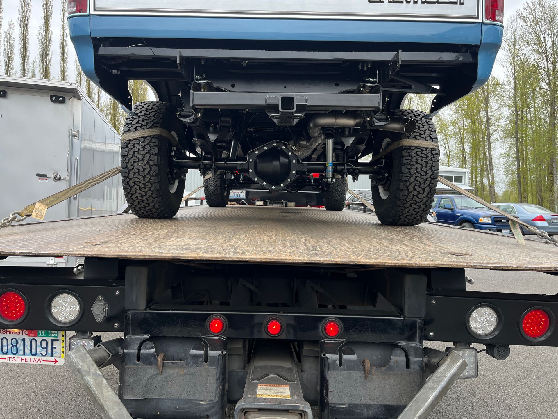 A blue truck is sitting on top of a flatbed tow truck.