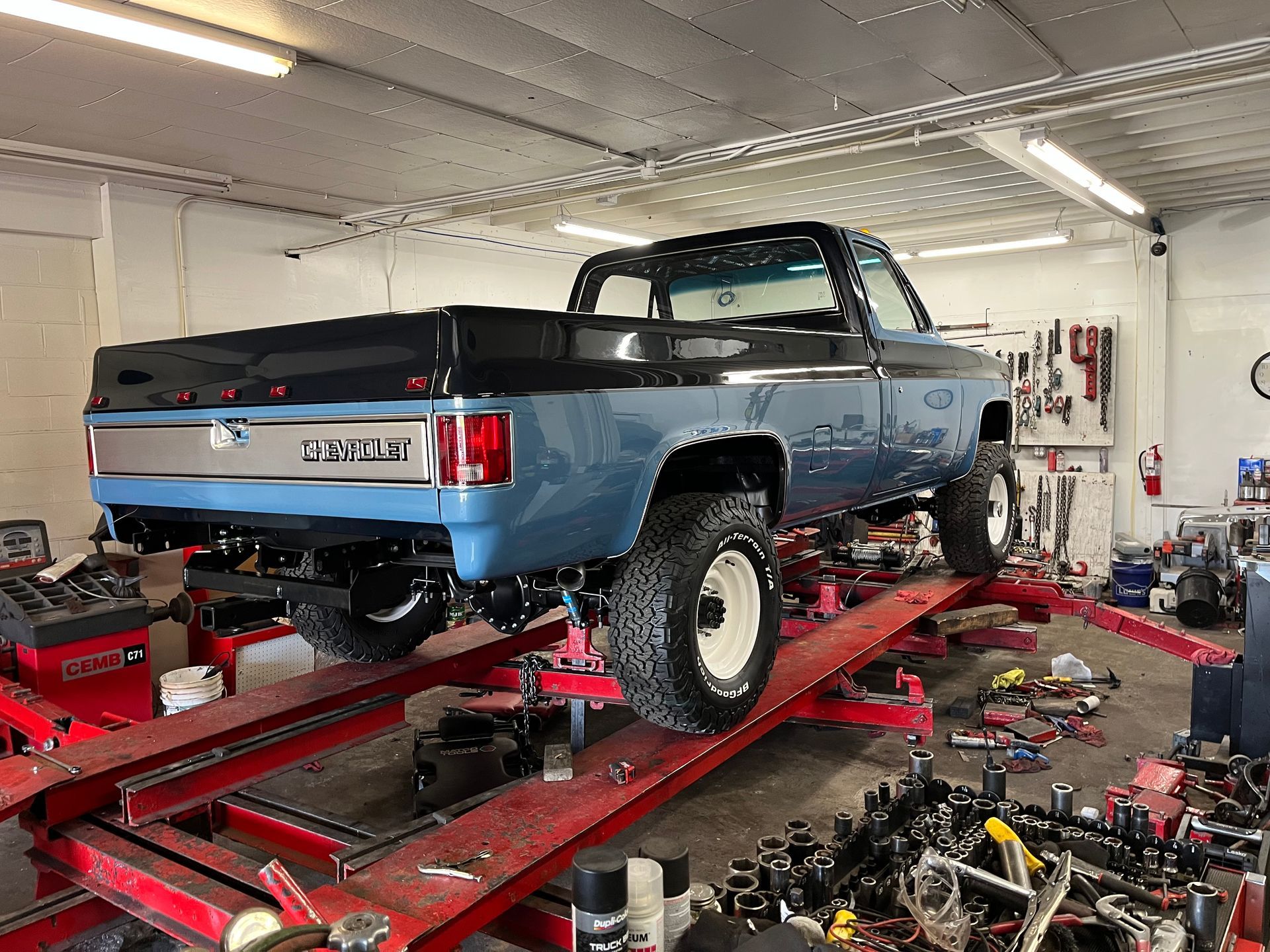 A blue truck is sitting on top of a red ramp in a garage.