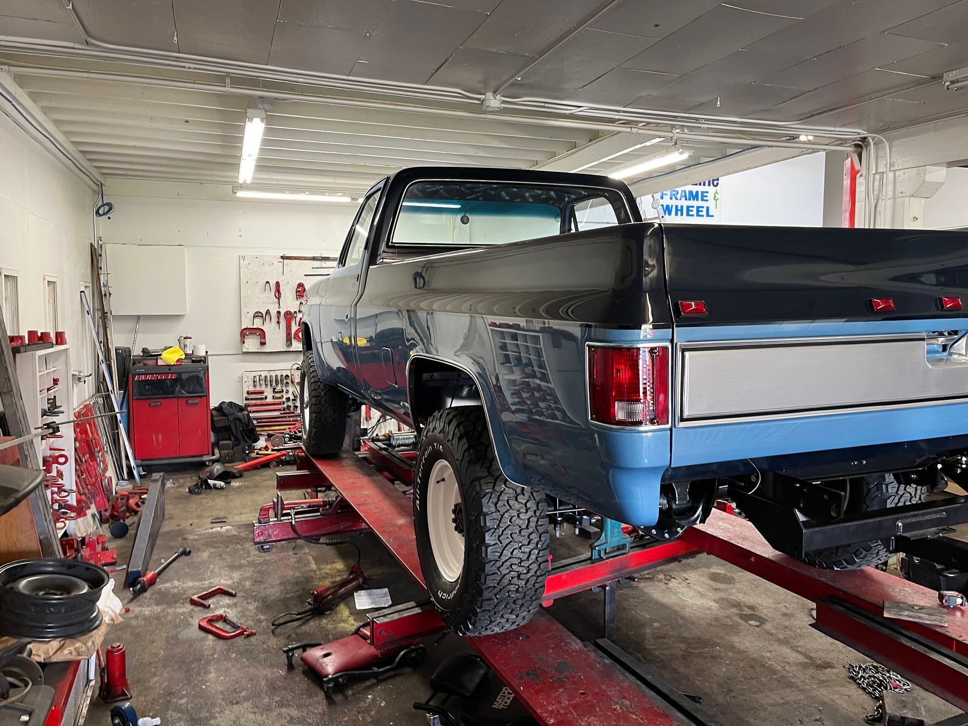 A truck is sitting on a lift in a garage.