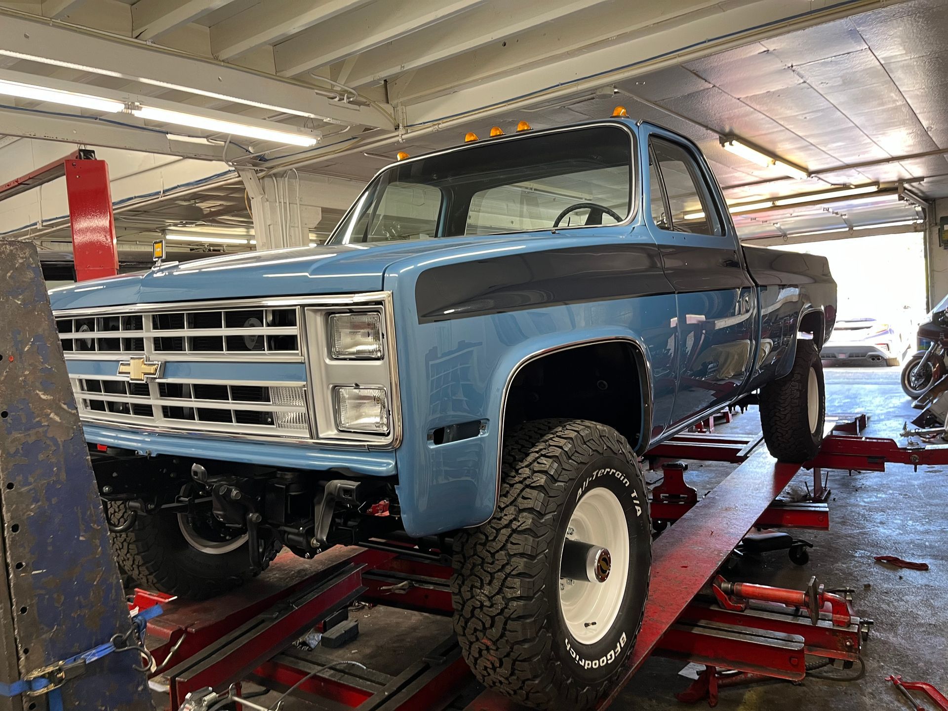 A blue truck is sitting on a lift in a garage.